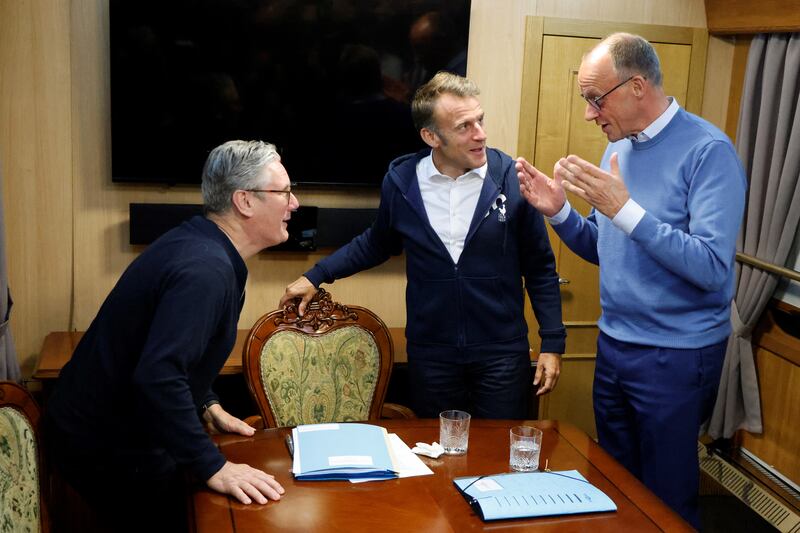 Britain's Prime Minister Keir Starmer (L) and France's President Emmanuel Macron (C) listen to German Chancellor Friedrich Merz during a trilateral meeting on board a train to Kyiv, in Shegyni, Ukraine, on May 9, 2025.