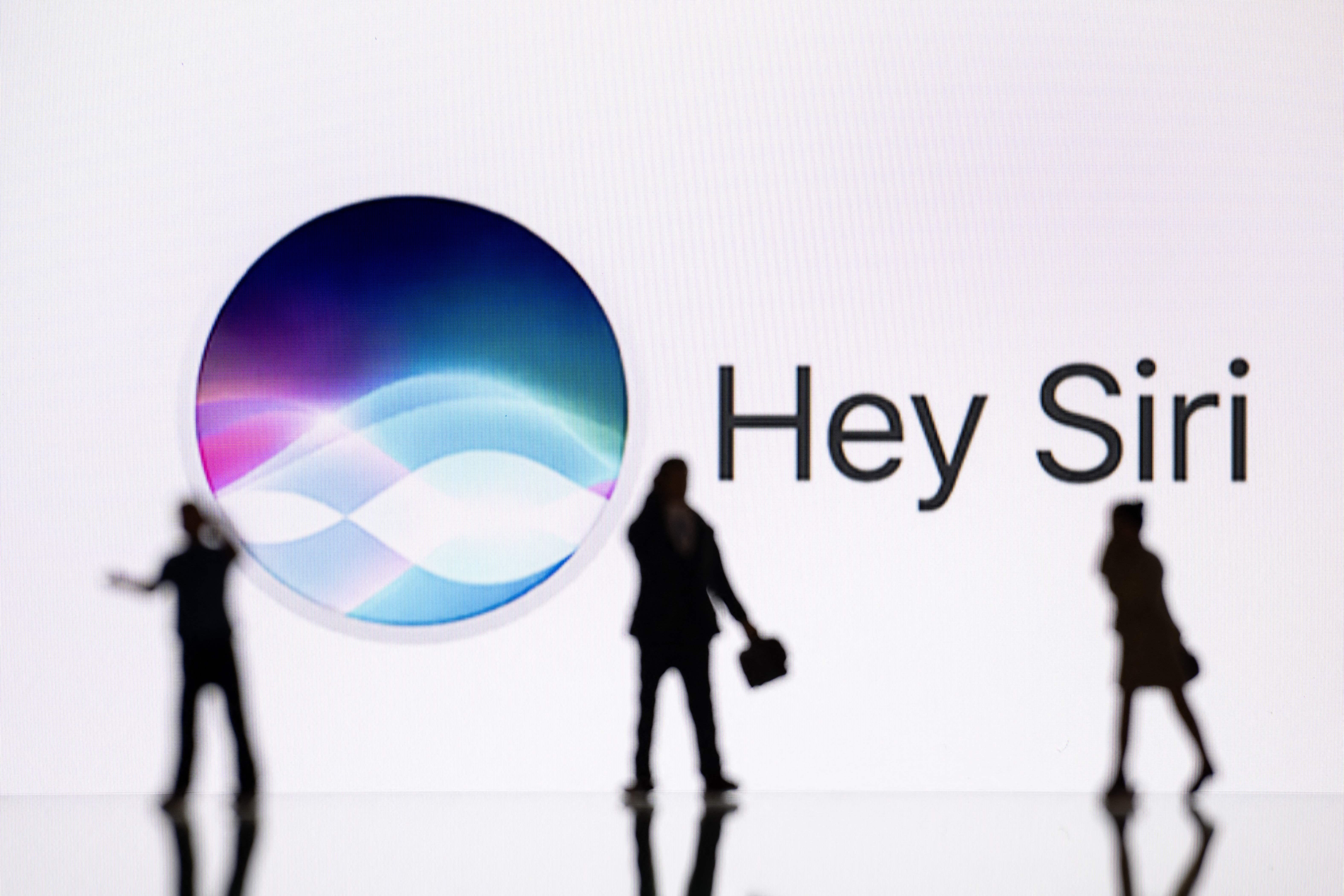 Silhouettes in front of "Hey Siri" signage