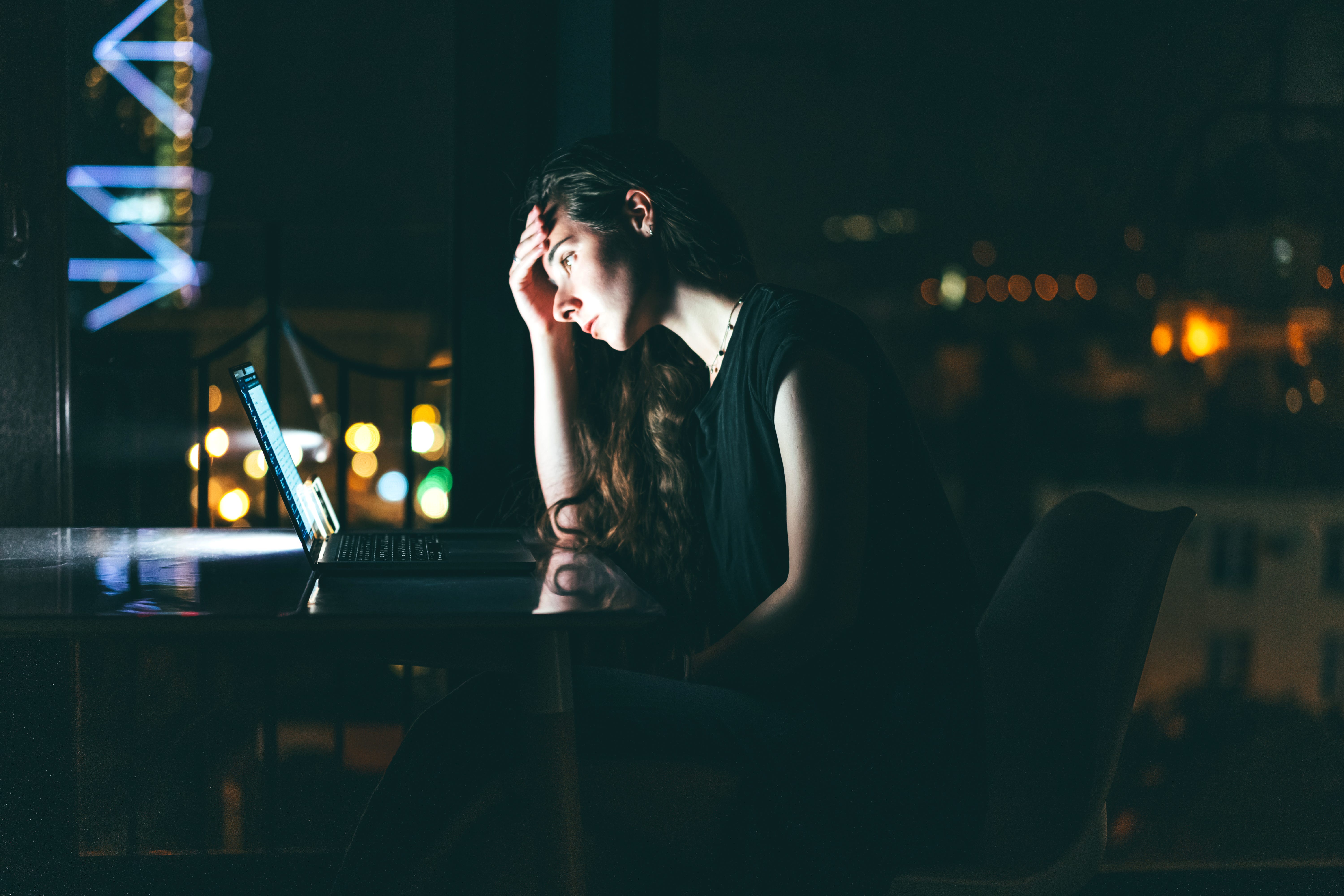 A woman working late on her laptop, burning out