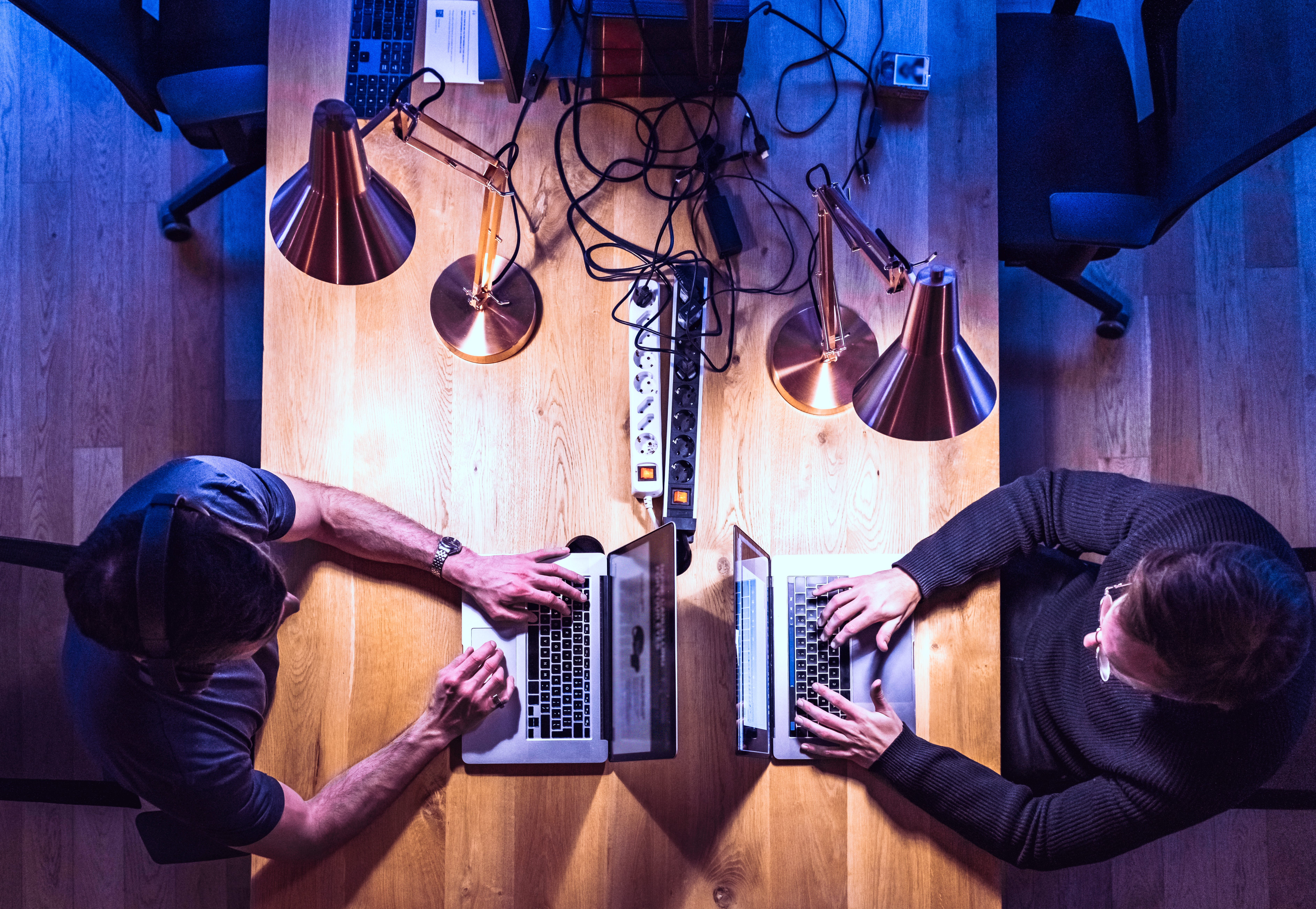 Overhead view of two coworkers working on laptops