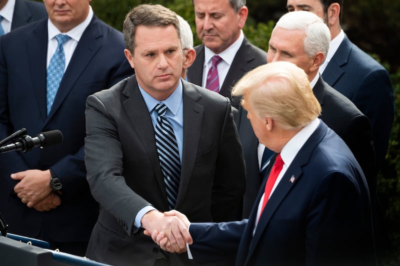 President and CEO of Walmart Inc. Doug McMillon (C) shakes hands with President Trump in 2020.