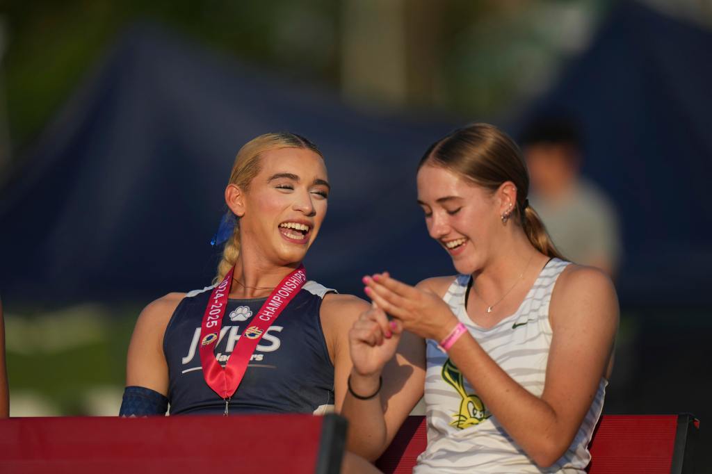 AB Hernandez laughs with a female high jumper during the medal ceremony after winning the girls' high jump gold.