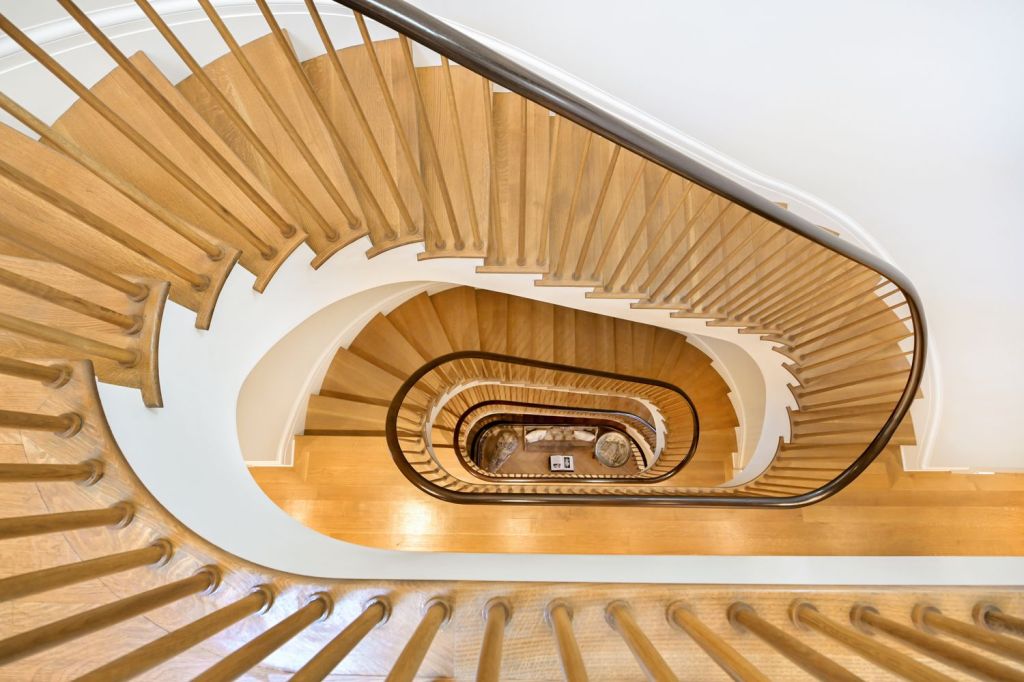 the spiral staircase with white walls and blonde wood tread and a dark wood rail