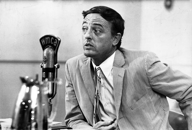 A black and white photo of William F. Buckley in a radio station before a microphone