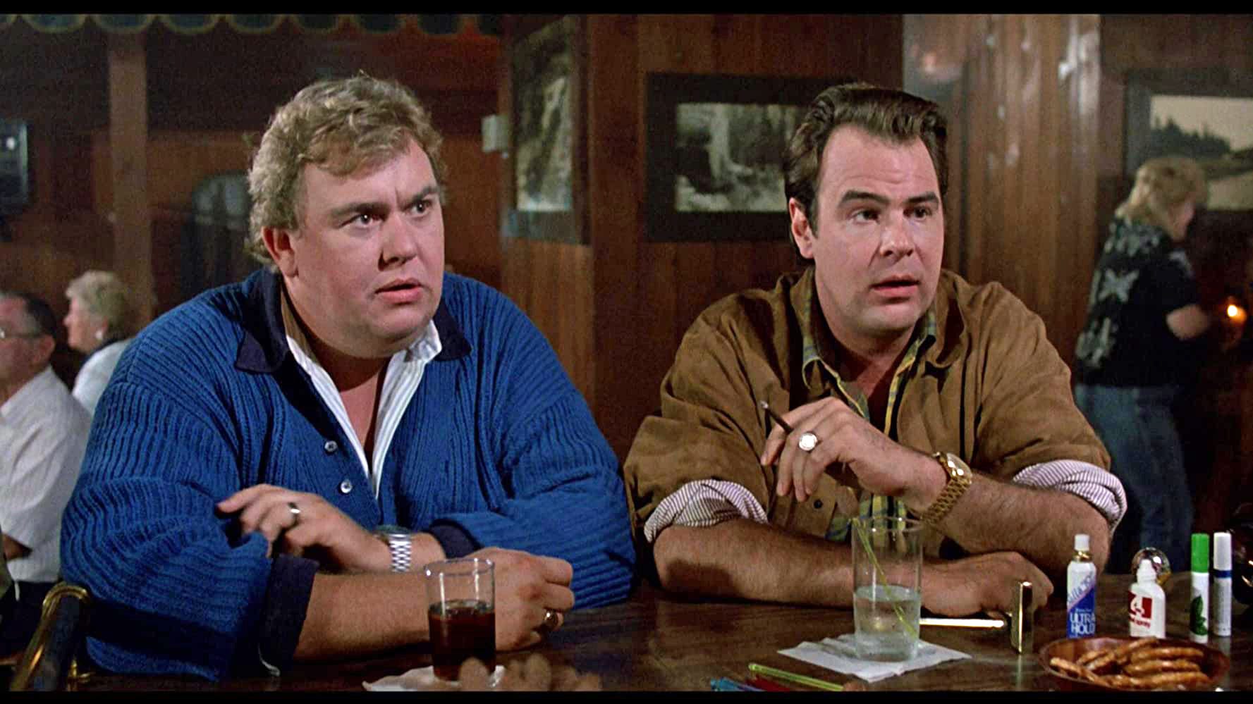 John Candy and Dan Aykroyd sitting at a bar