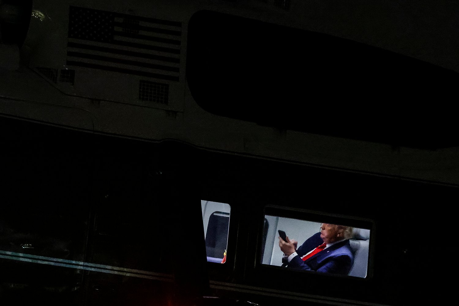 Donald Trump is seen inside a helicopter at night looking down at a cell phone