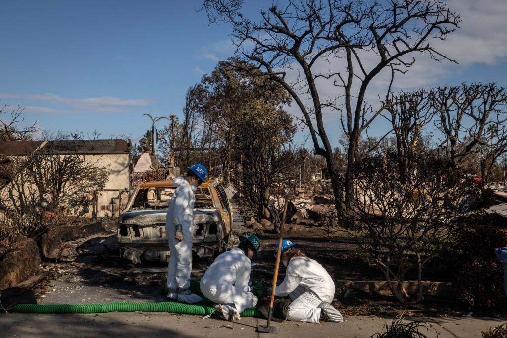 Inspectors survey a ruin after the Palisades Fire.