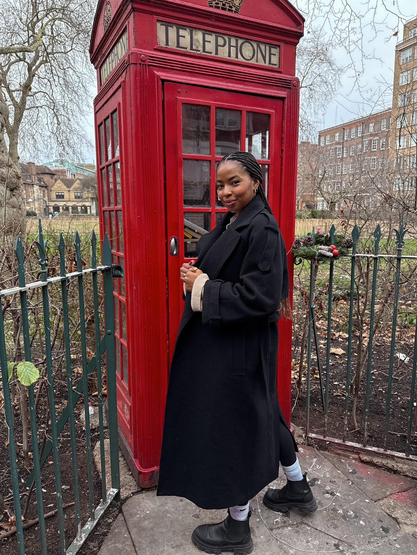 Kira West posing outside of a red London phone booth.