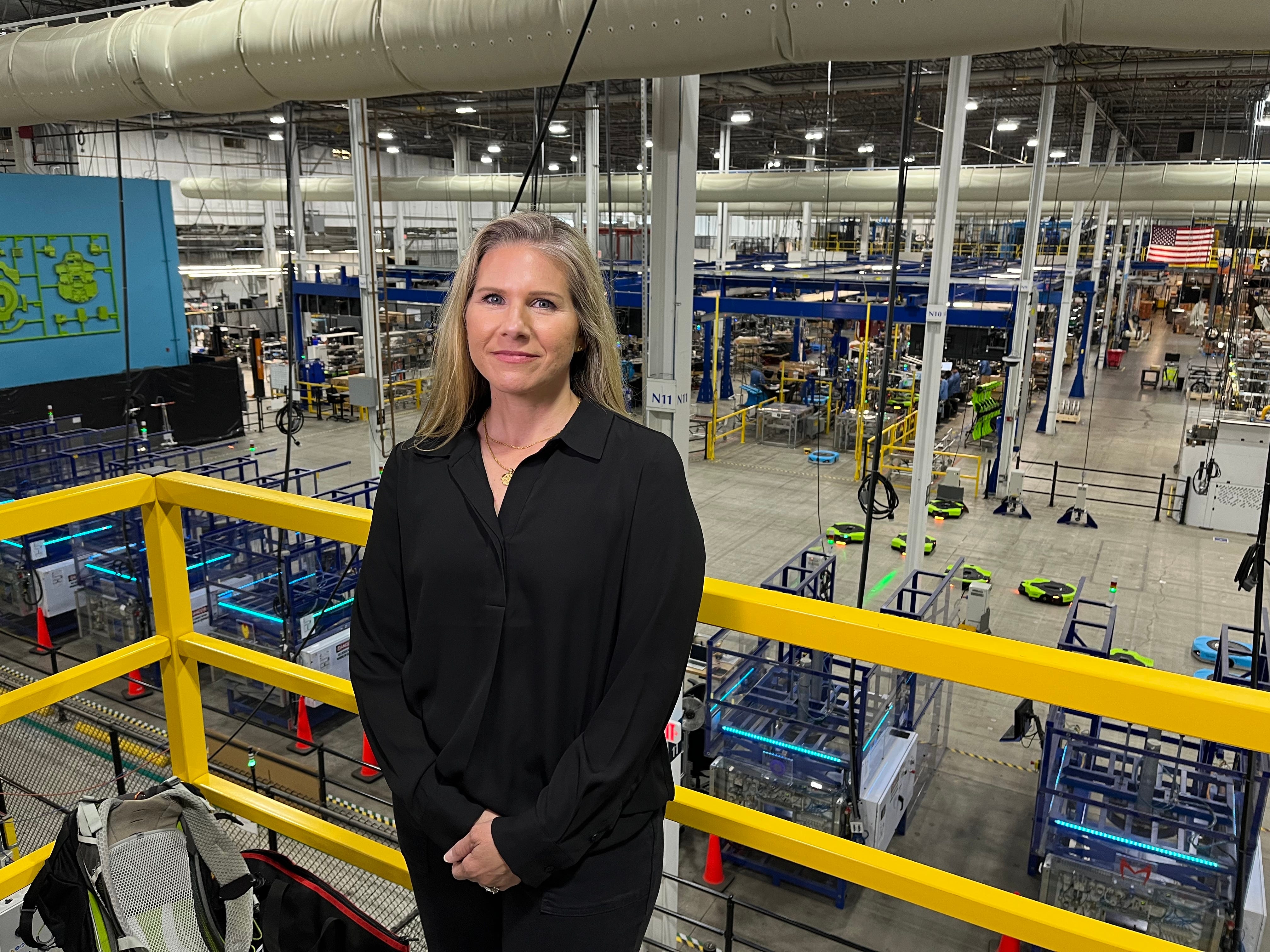 Julie Mitchell, director of robotic sortation technology at Amazon Robotics, inside Amazon's West Reading facility with robots and manufacturing in the background