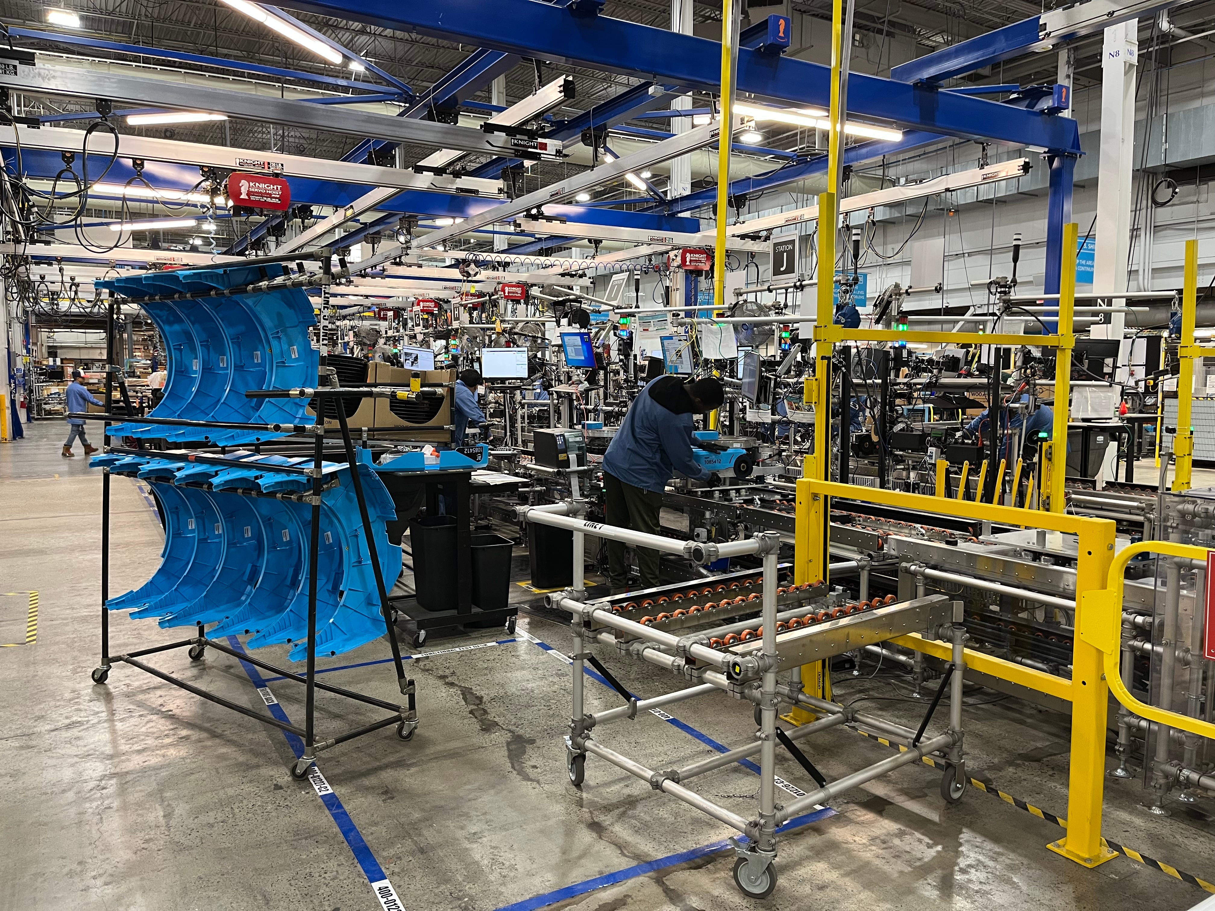 Employee assembles blue Amazon robot on manufacturing line