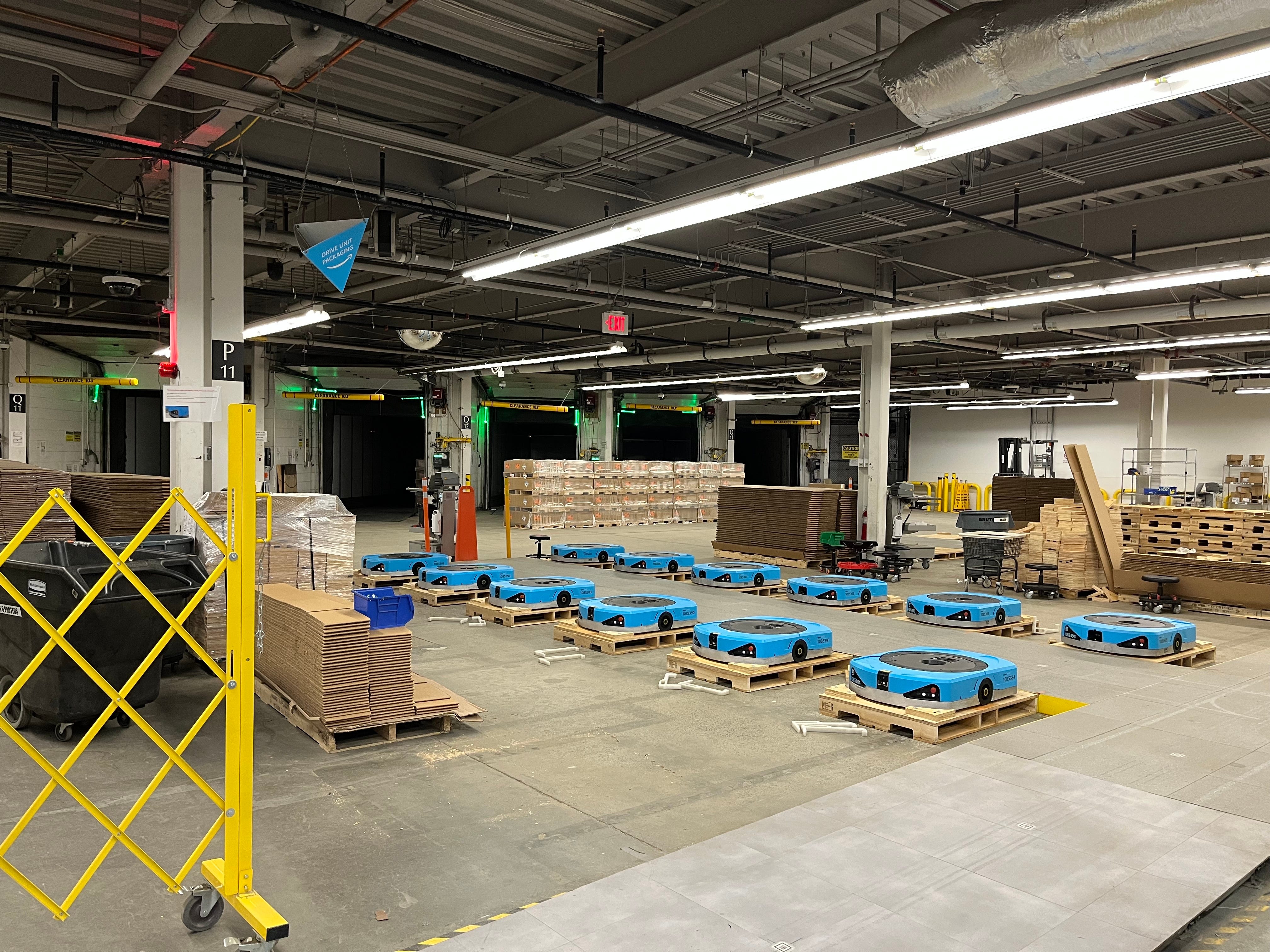 Blue Amazon robots sit on individual pallets before they are shipped out