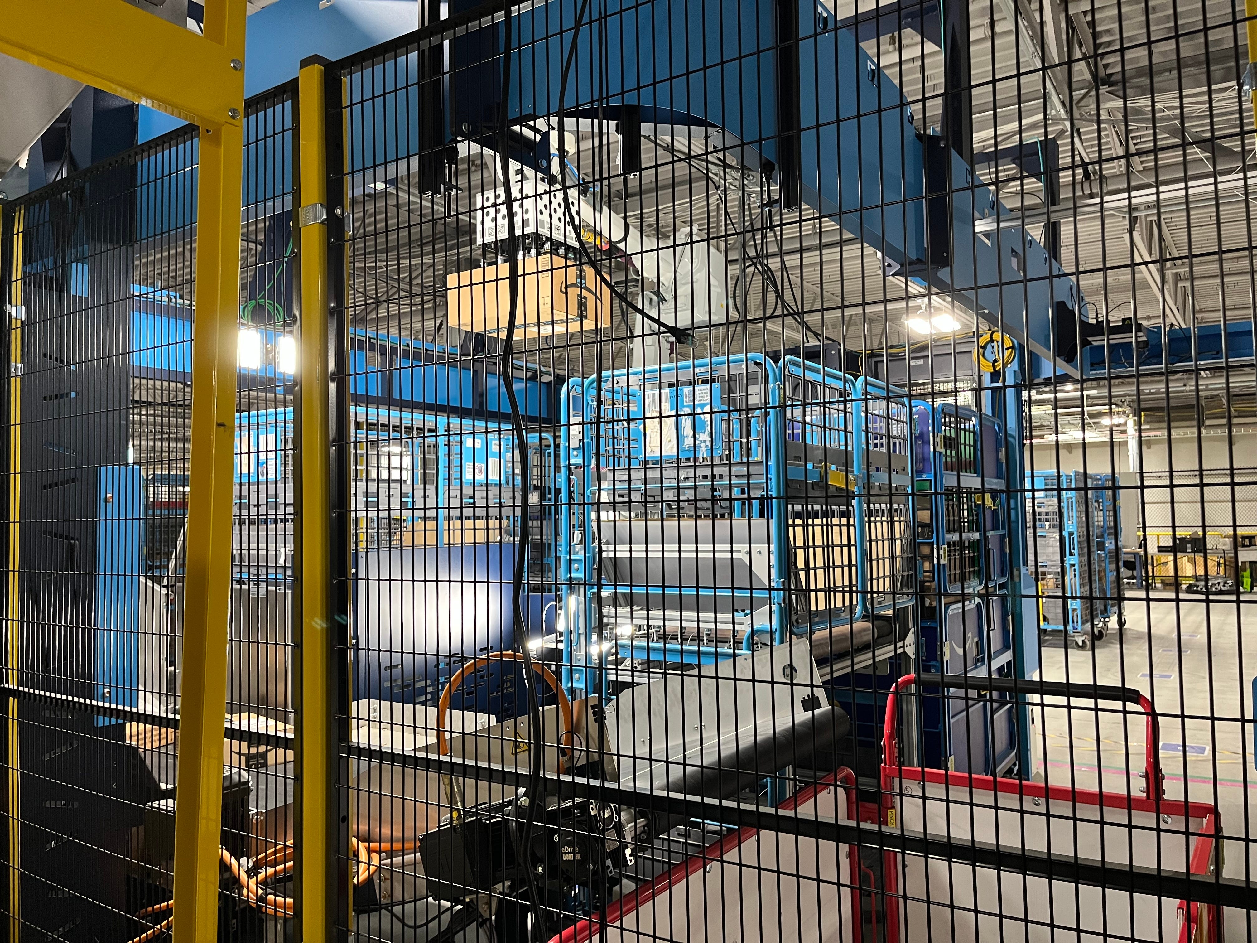 Robotic arm lifts package in Amazon Robotics facility
