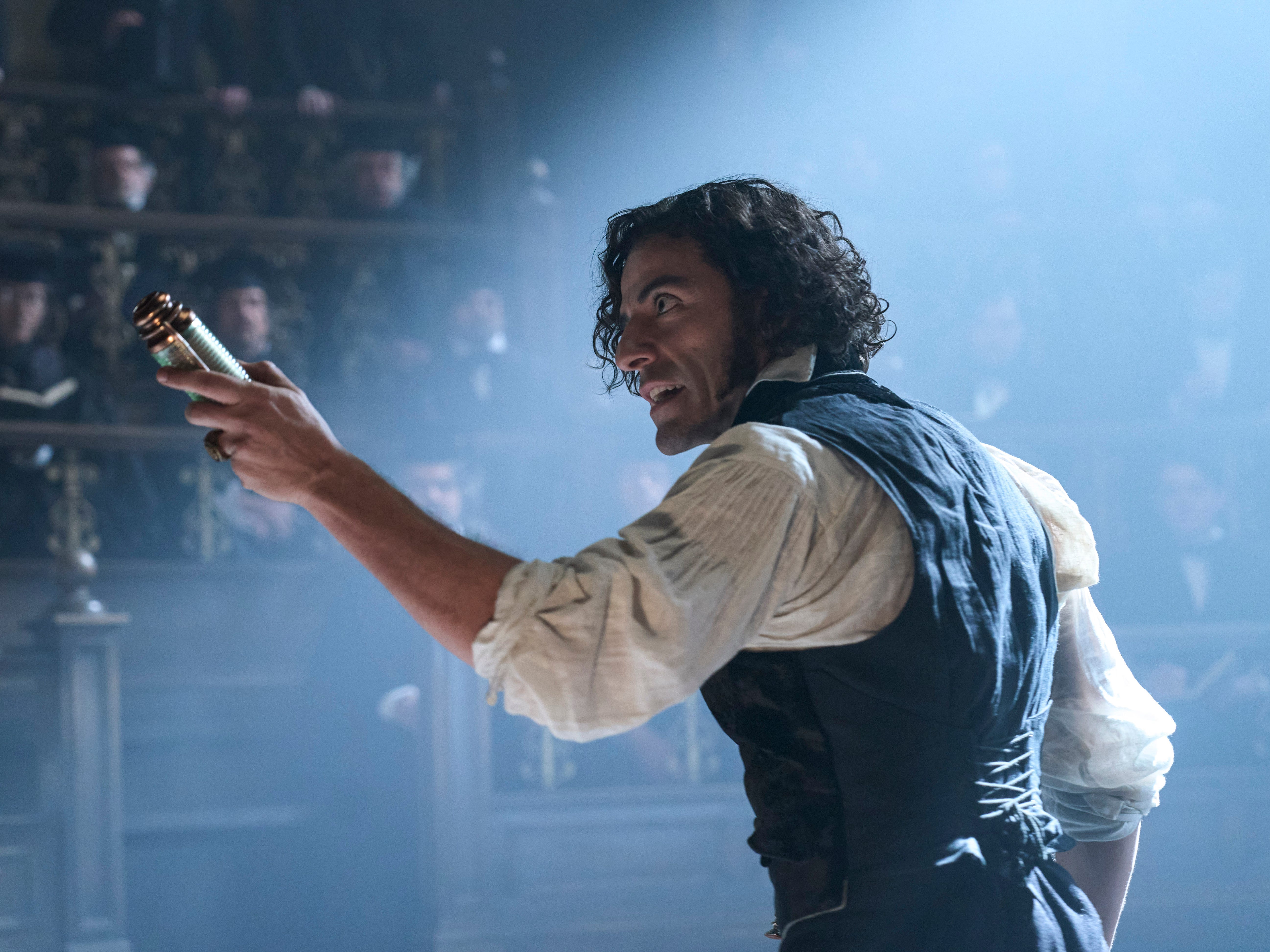 A still from "Frankenstein" showing Oscar Isaac holding an object with his right hand.