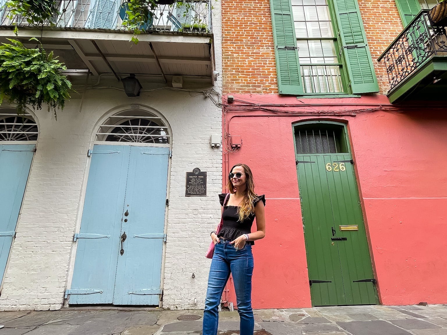 Emily stands in front of colorful buildings with balconies in New Orleans.