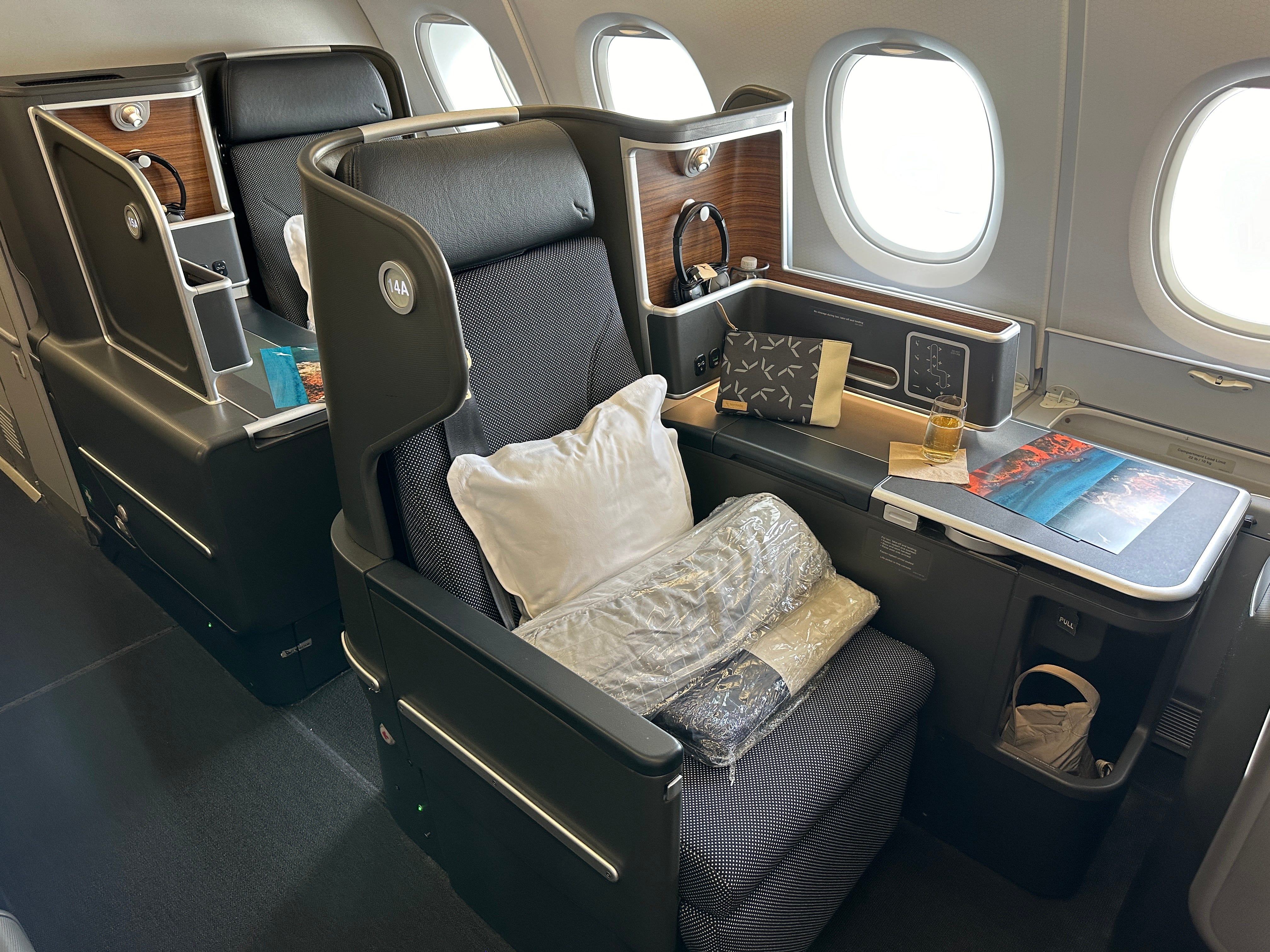 Business class seat on Qantas flight with pillow, bedding on the seat and side shelf area with storage
