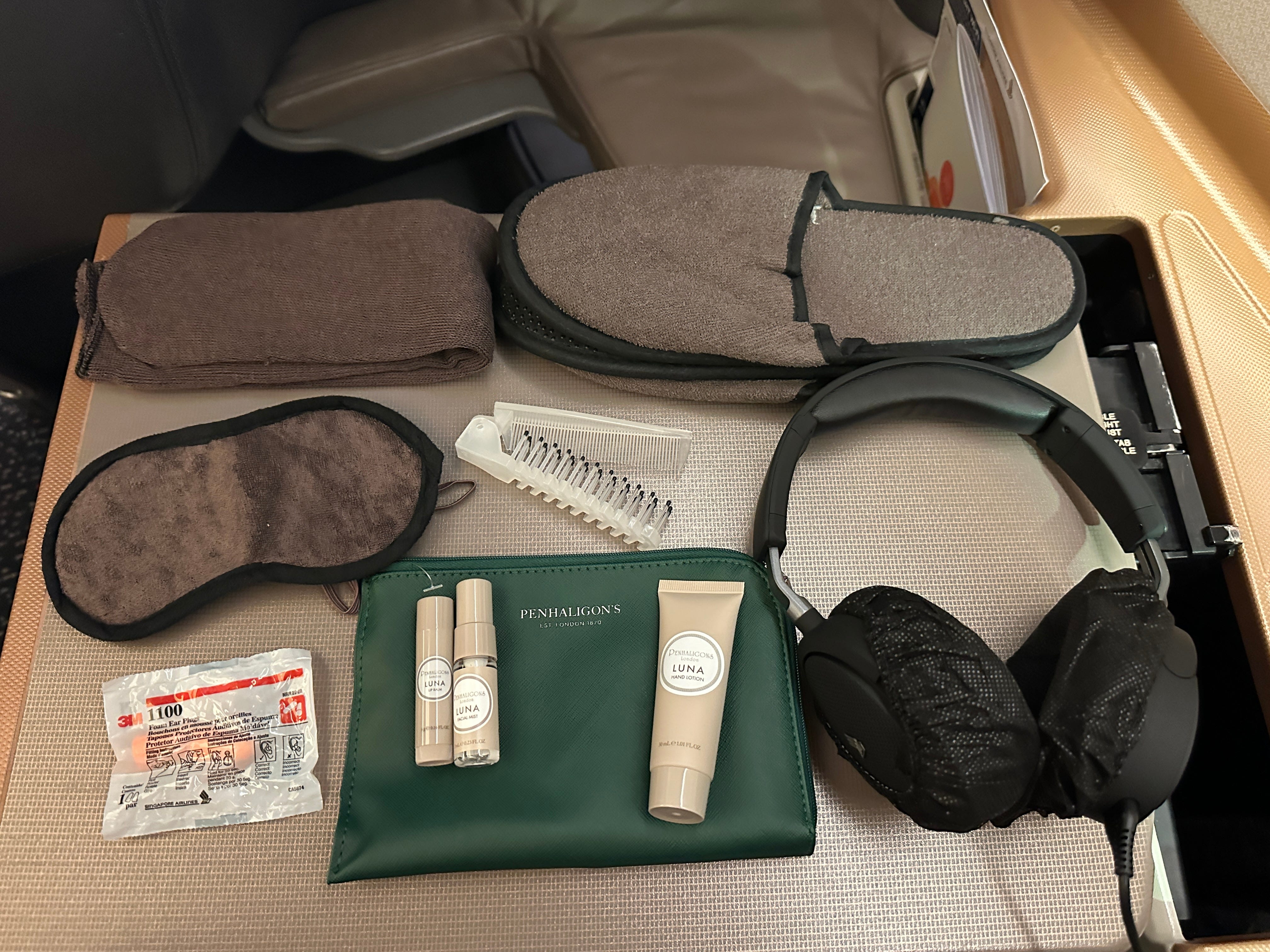 Contents of amenity kit on table tray with items like toiletries, headphones, slippers, socks