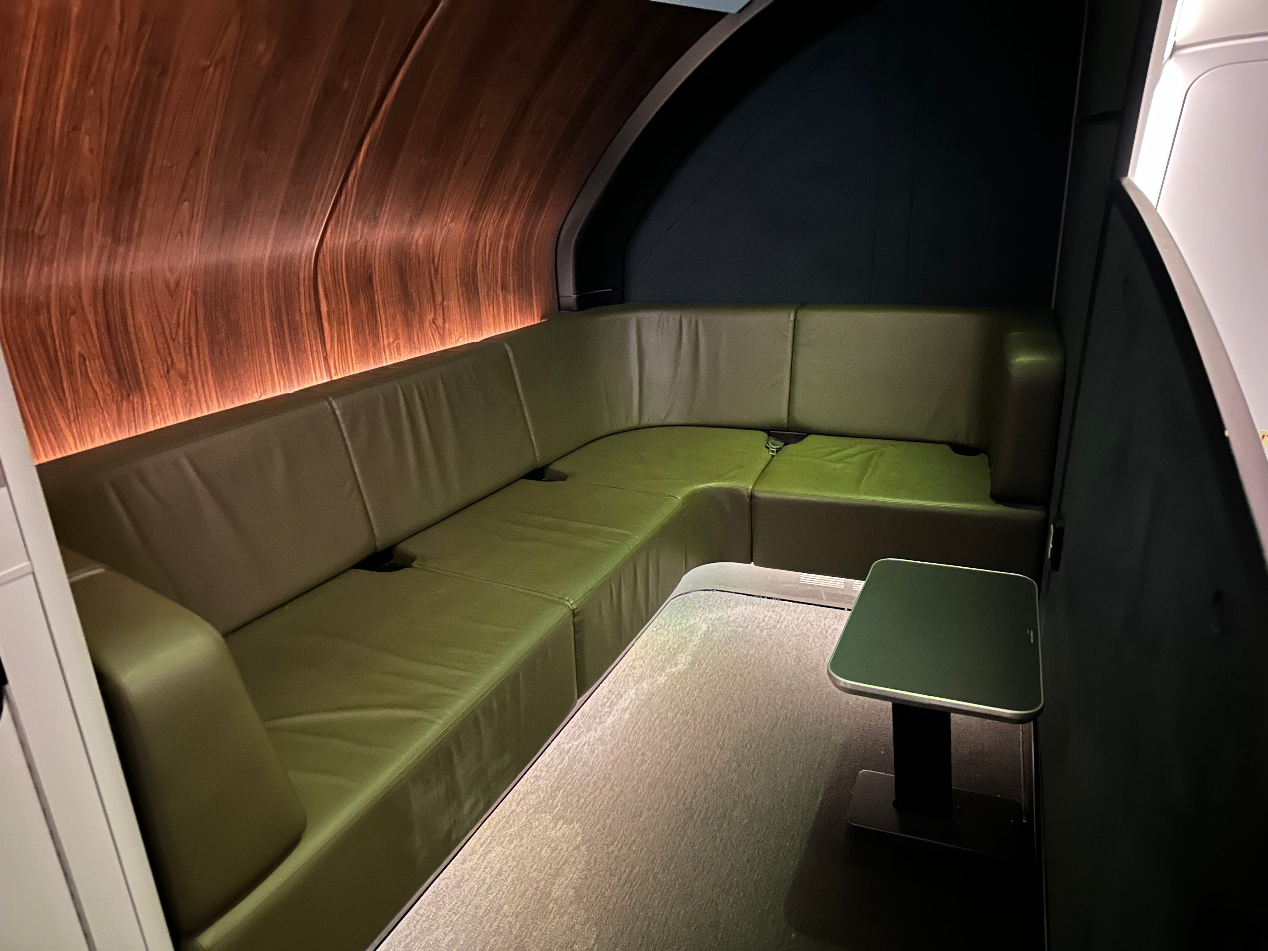 Curved green couch with small table on Qantas plane