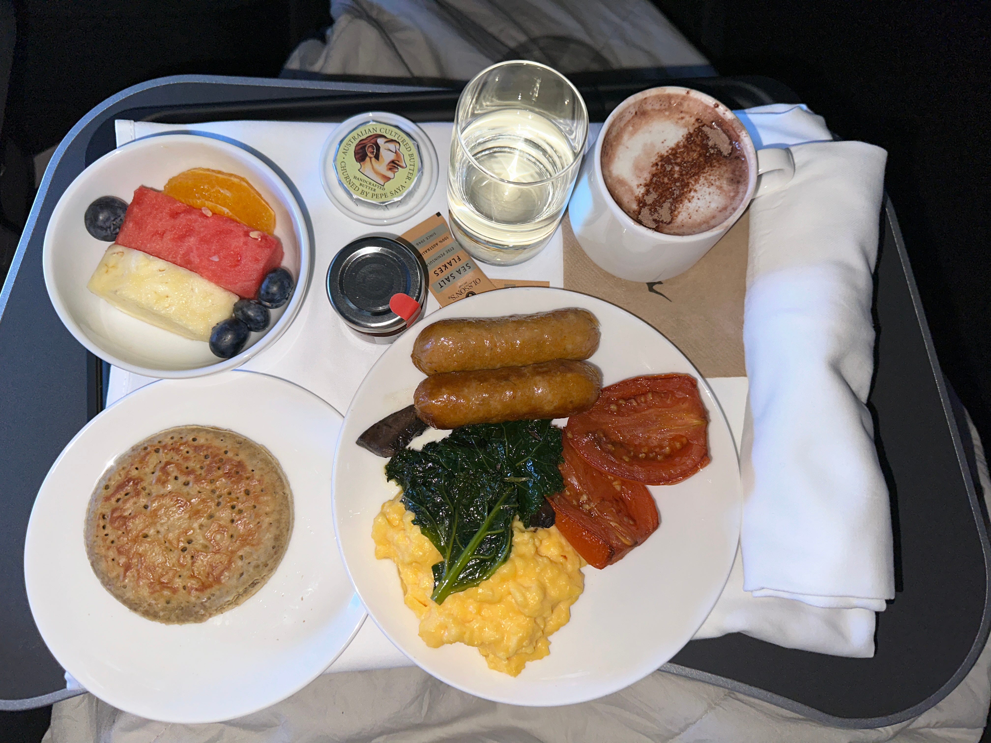 Aerial view of eggs, tomatoes, sausage, hot chocoalte, fruit breakfast on airplane tray table on Qantas flight