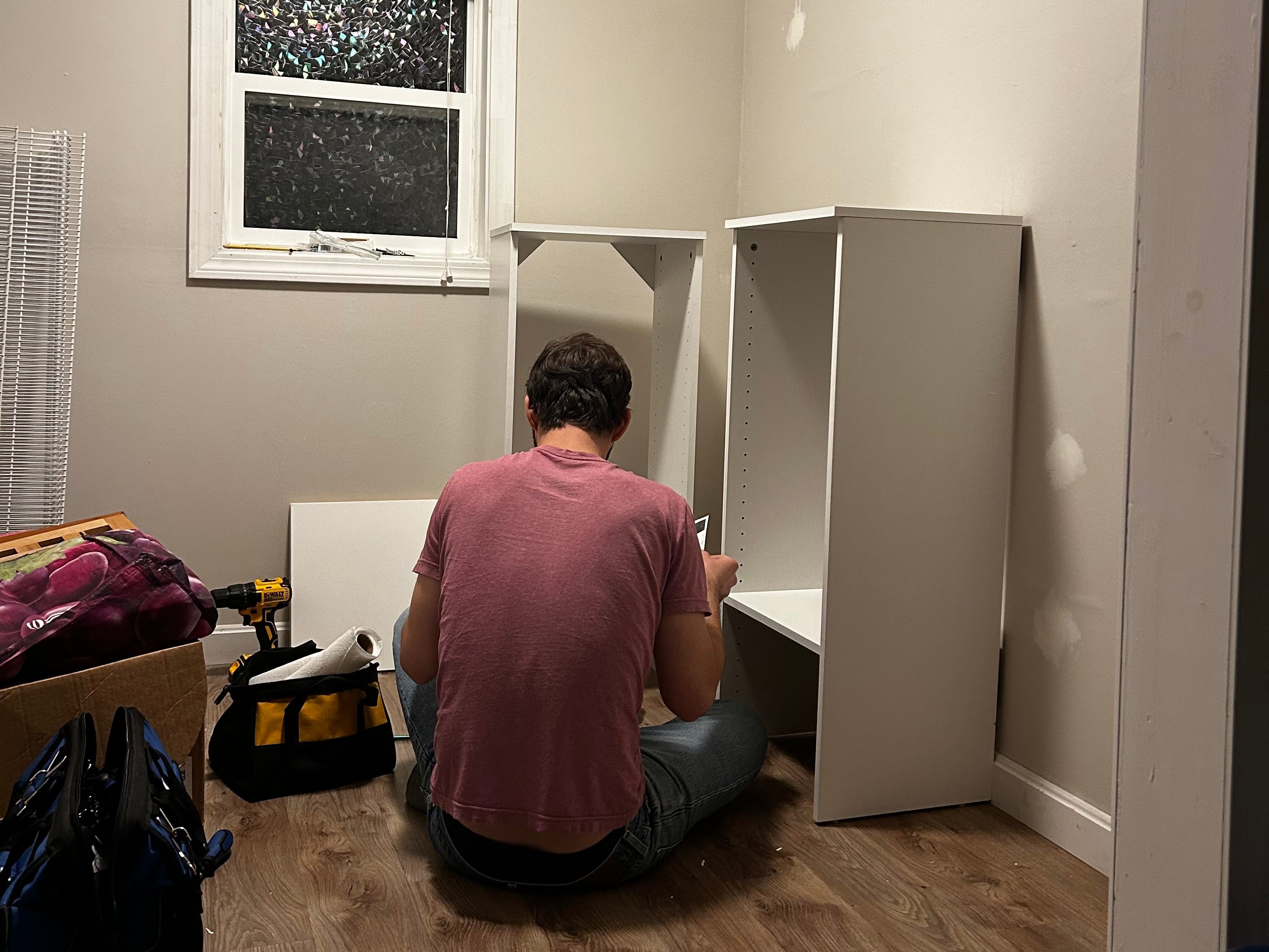 A man builds shelving in a closet.