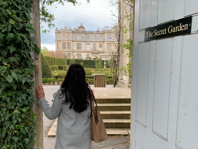 The writer poses in front of the doorway to a garden in the UK.