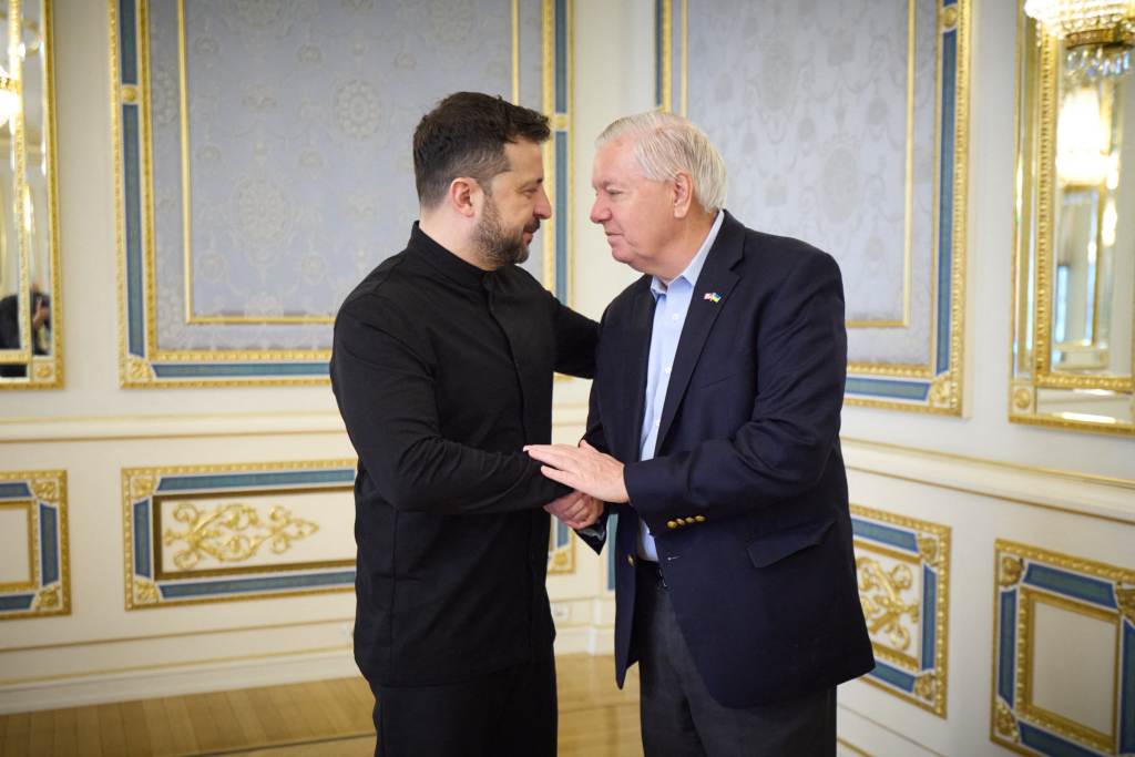 Volodymyr Zelensky and Lindsey Graham shaking hands.