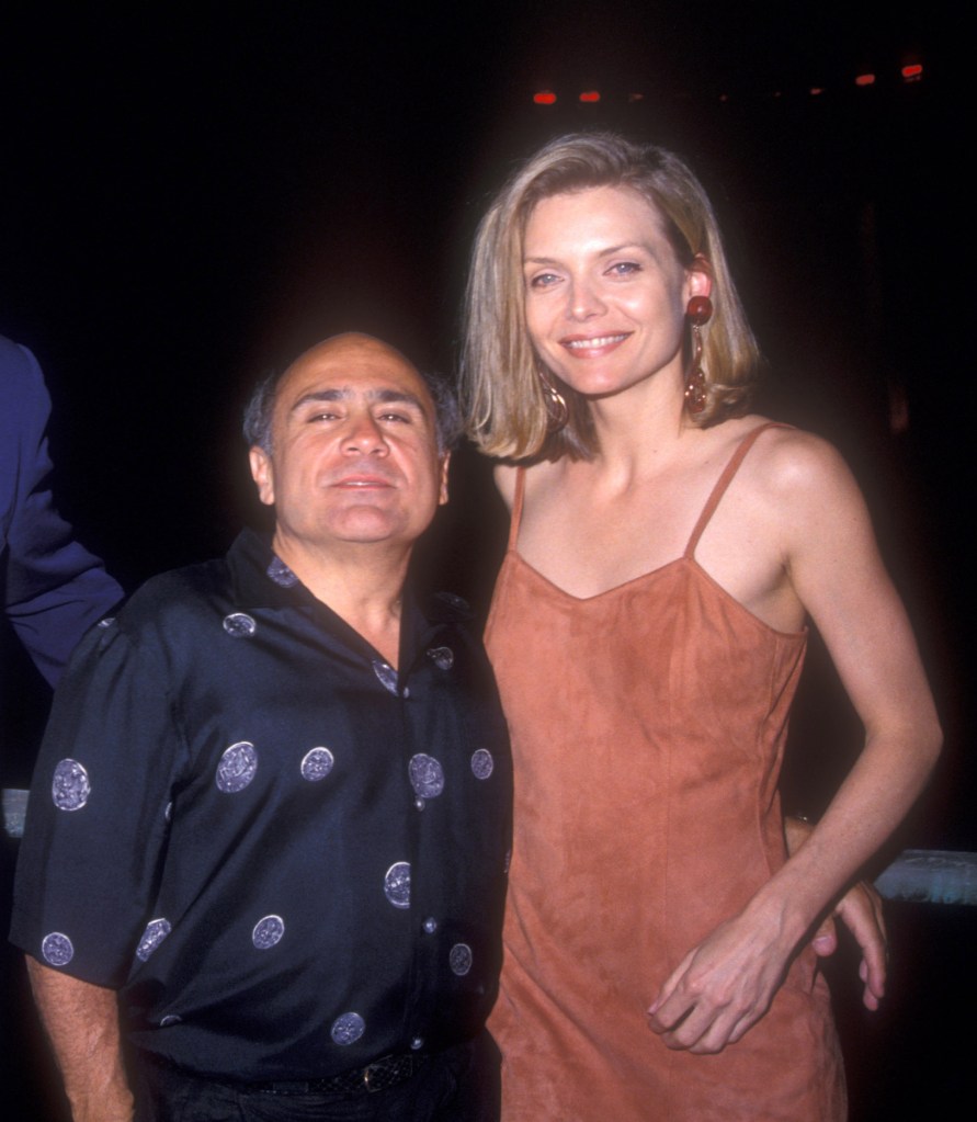 Michelle Pfeiffer and Danny DeVito pose together on a red carpet.