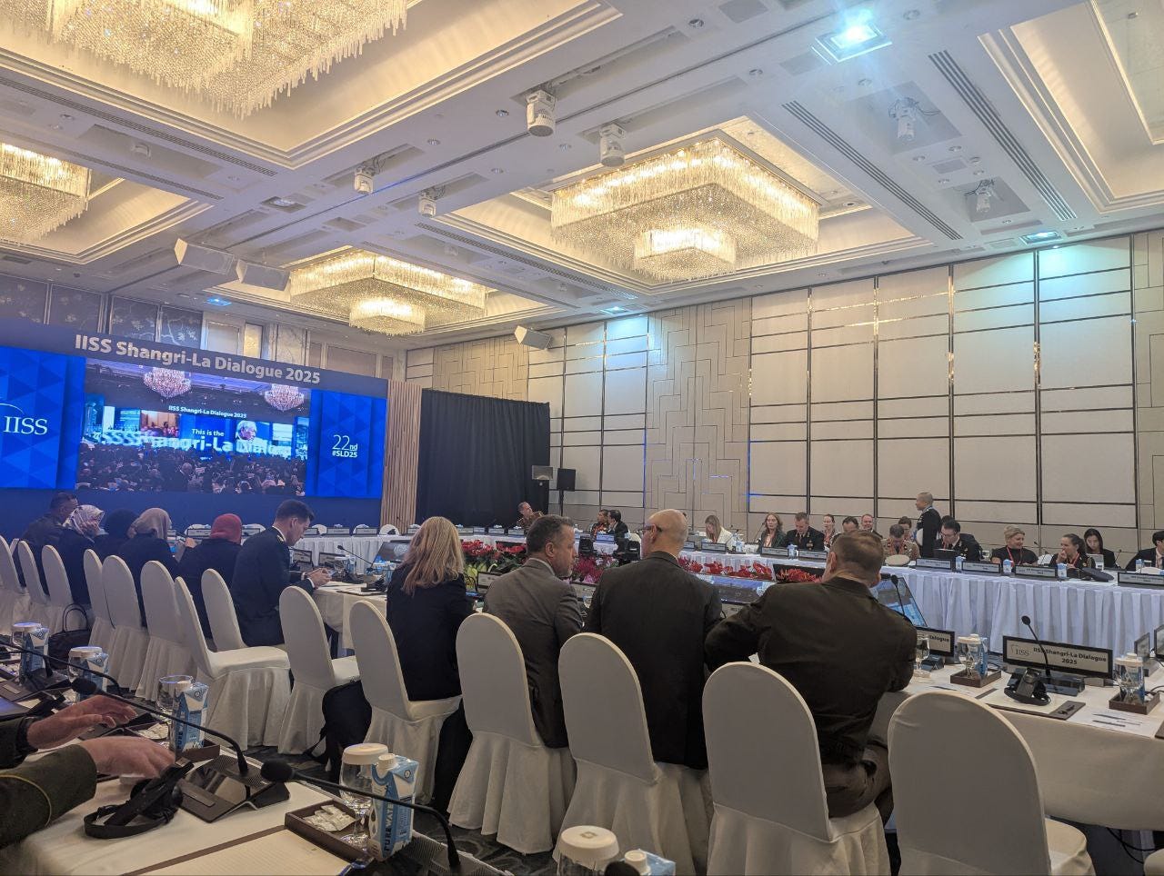 Delegates sit in a viewing room on the sidelines