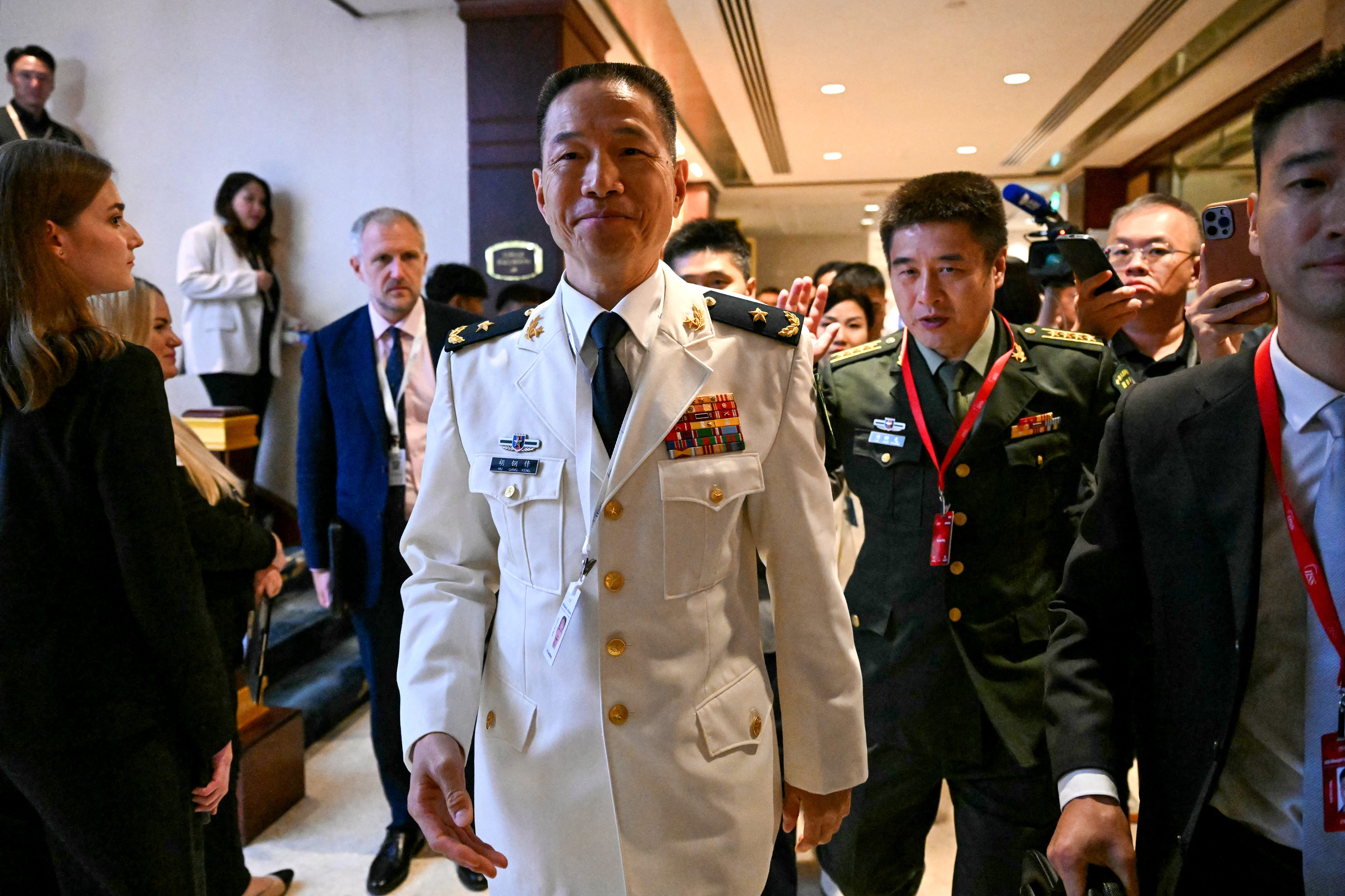 Hu Gangfeng and other Chinese officials walk past staffers and reporters at the Shangri-La hotel.