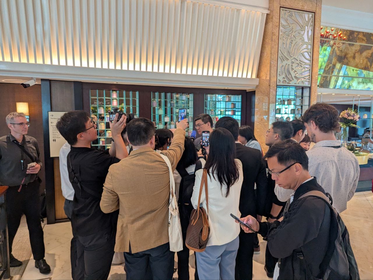 Chinese reporters speak to a professor at the top of a marble stairwell in the Shangri-La.