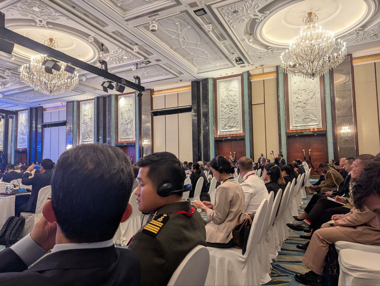 Officers, aides, staffers, and journalists take notes and listen to translations as the plenaries are conducted.