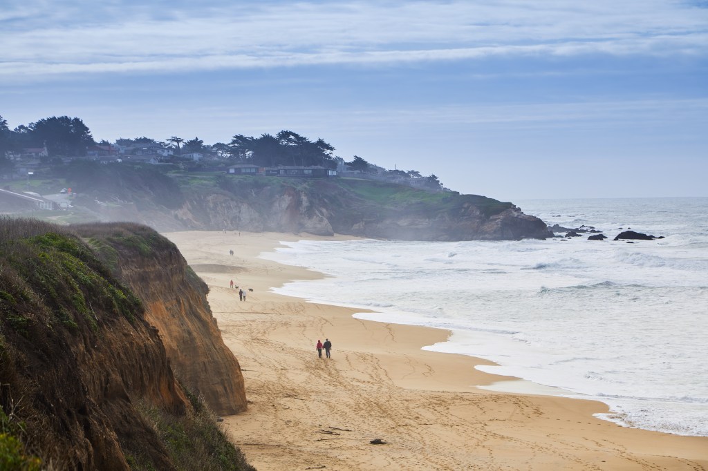 Montara State Beach in California with people walking on the sand.