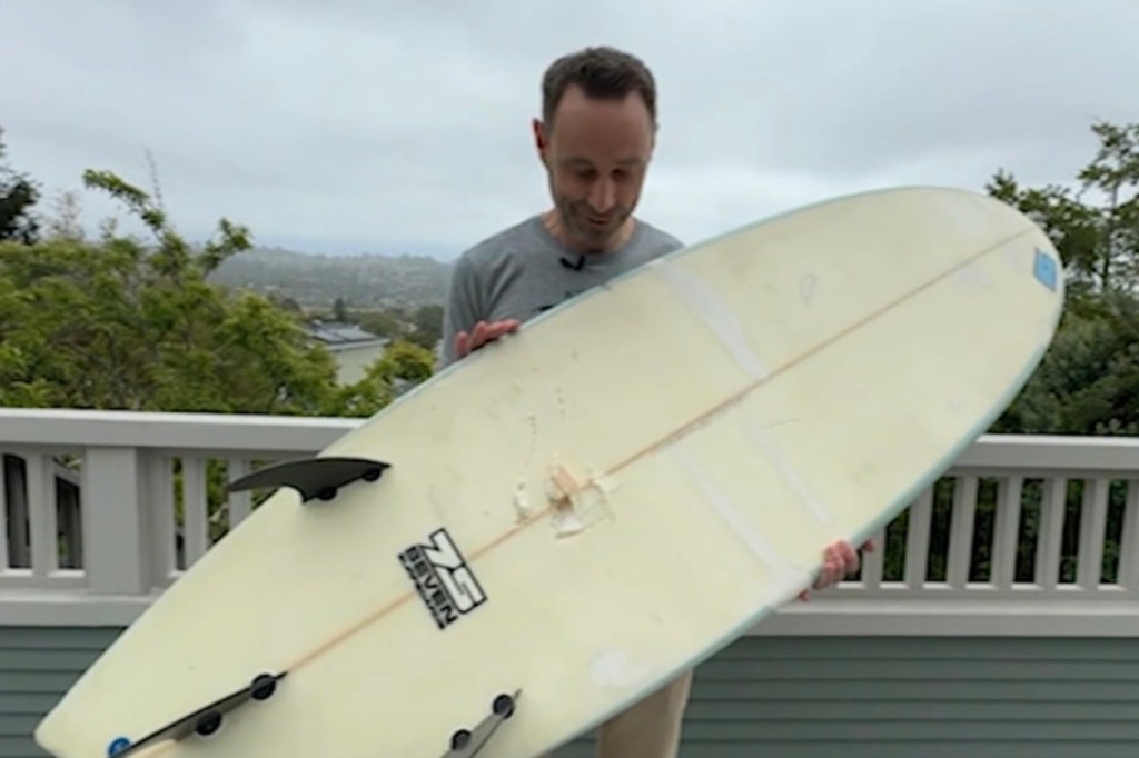 Man holding a damaged surfboard.
