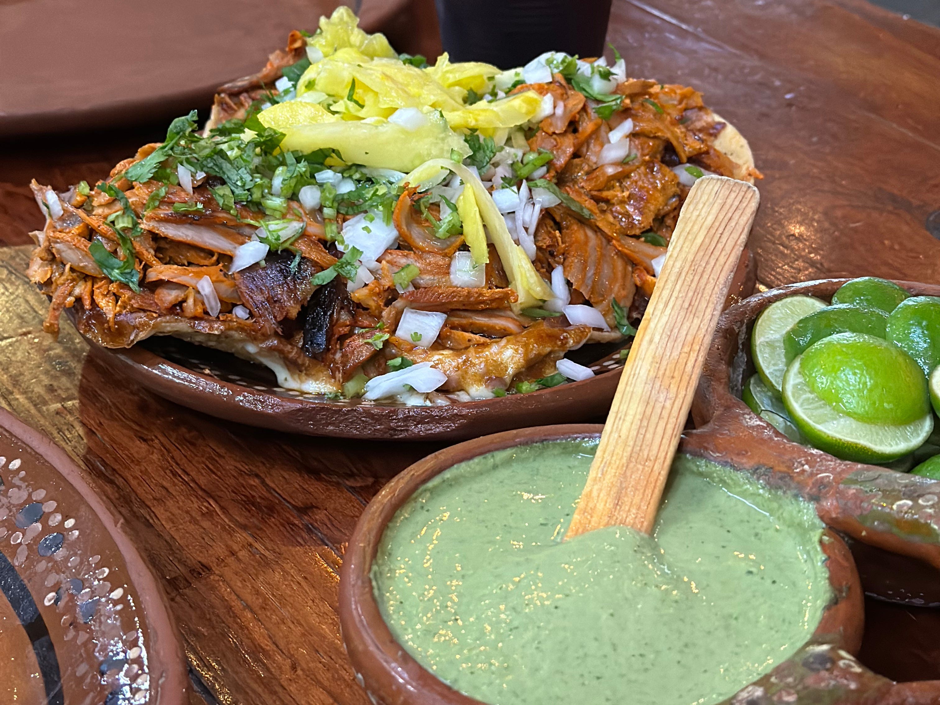 A plate of Mexican food and a variety of sauces on a table.