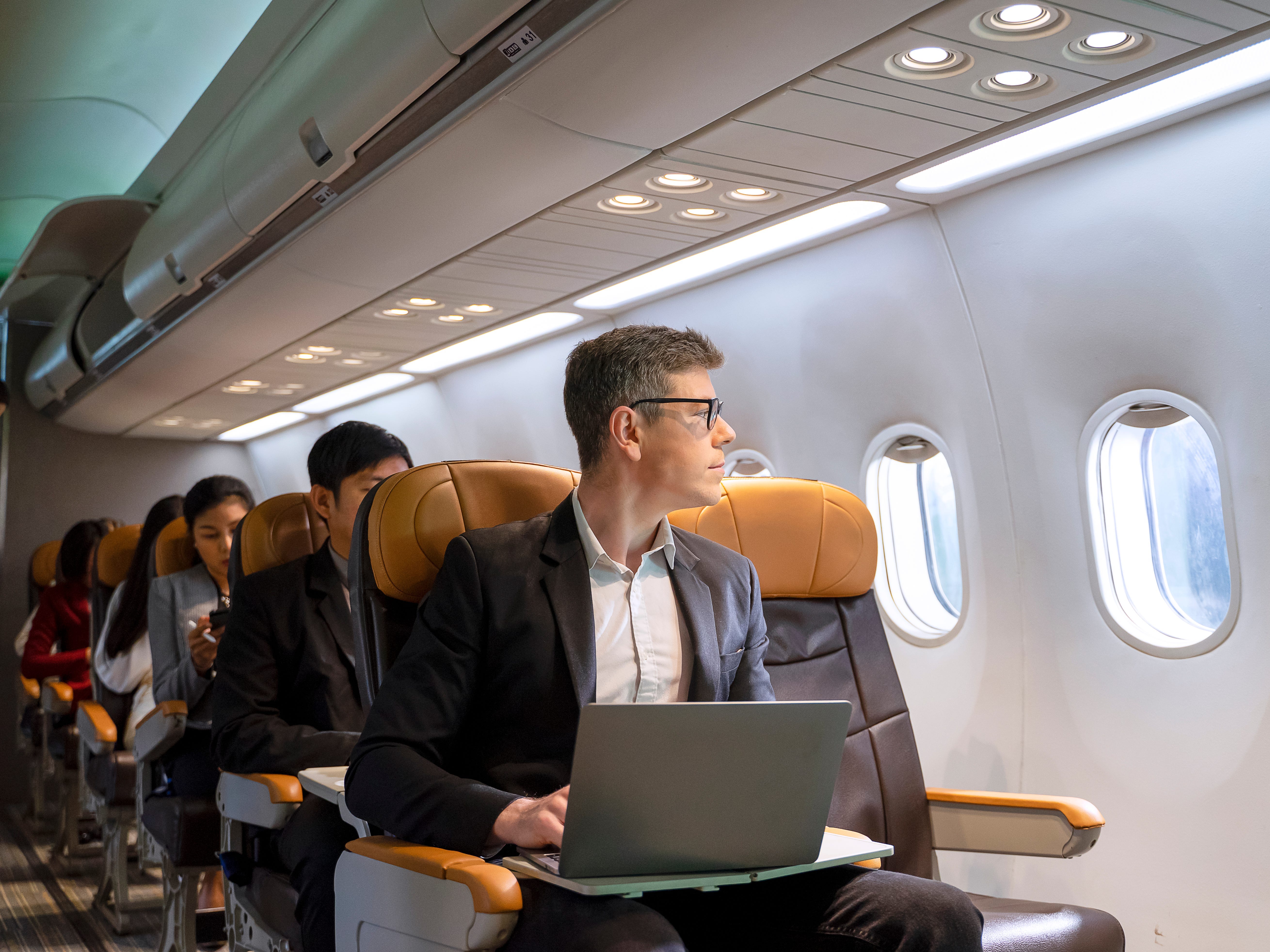 Passengers are sitting in the commercial plane. Cabin crew is take care passengers in the plane.