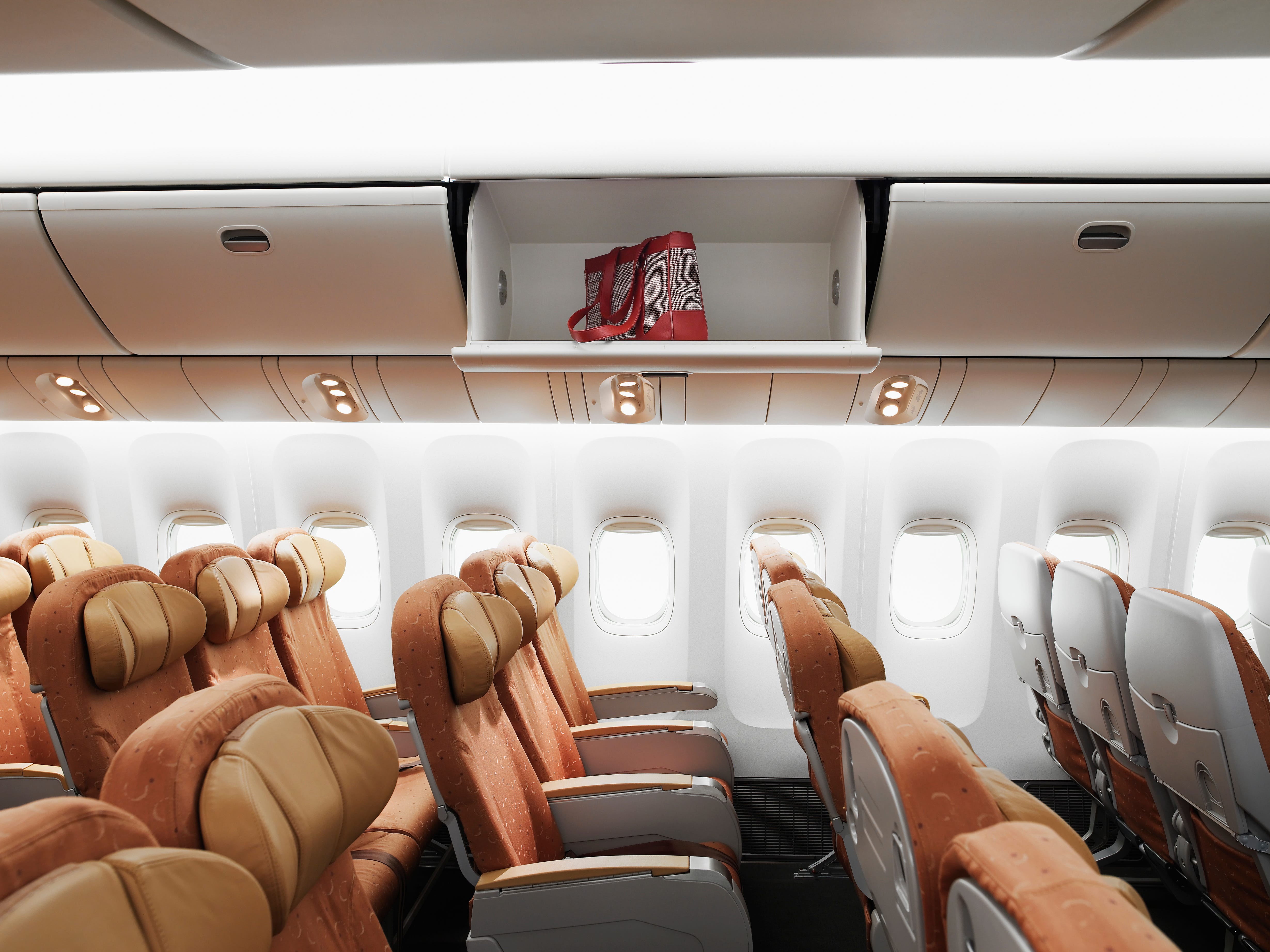 Empty airplane interior, bag left in overhead bin, side view