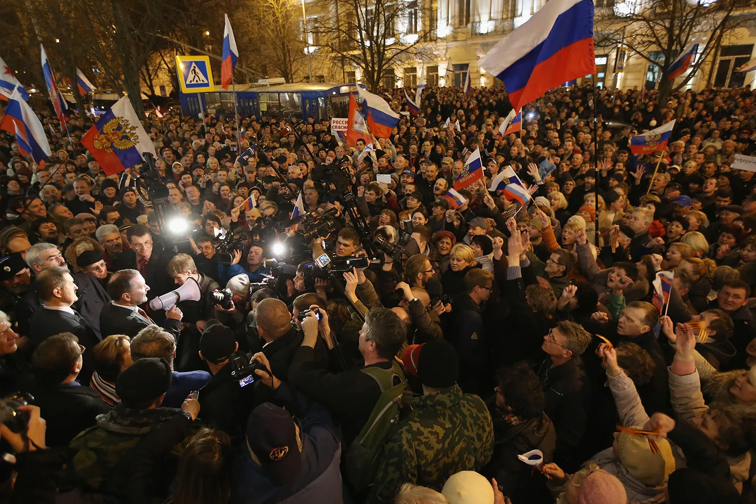 A large crowd at night saves Russian flags.