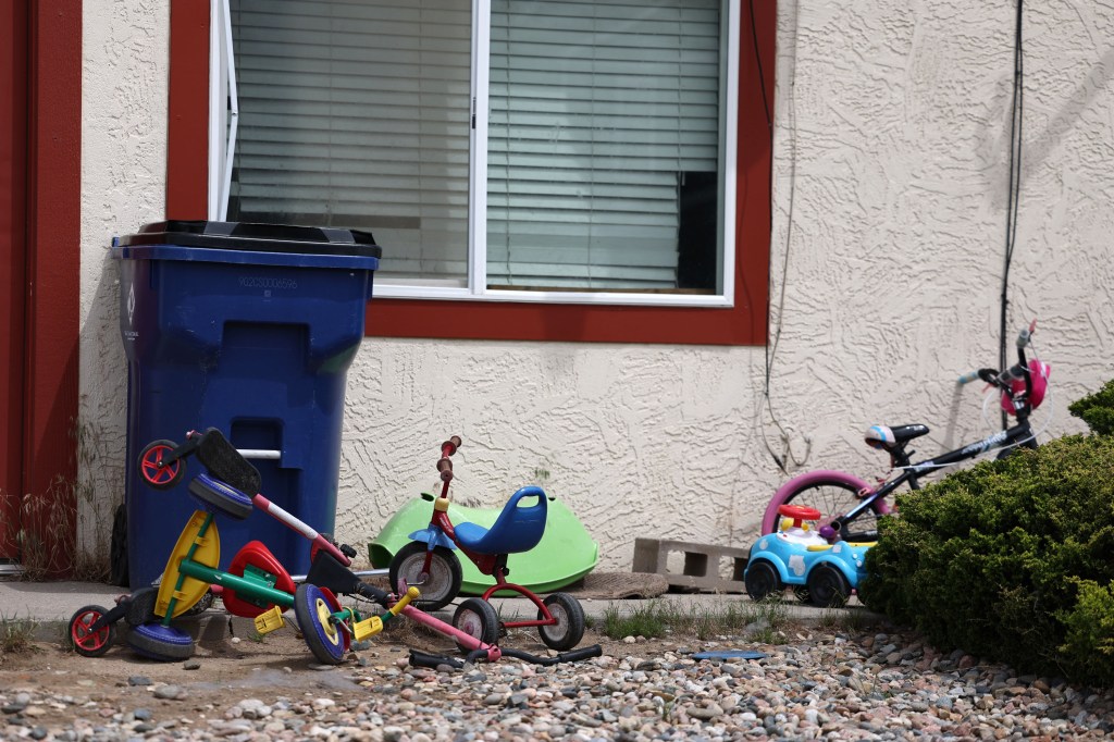 Exterior of a home with children's toys and a blue recycling bin.