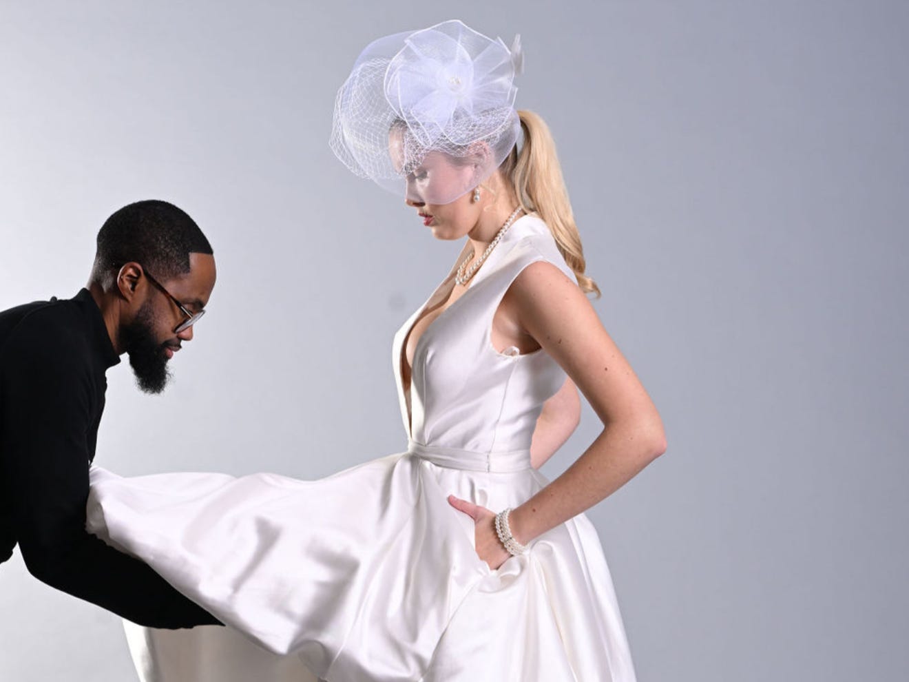 a man picks up a wedding dress skirt on a model