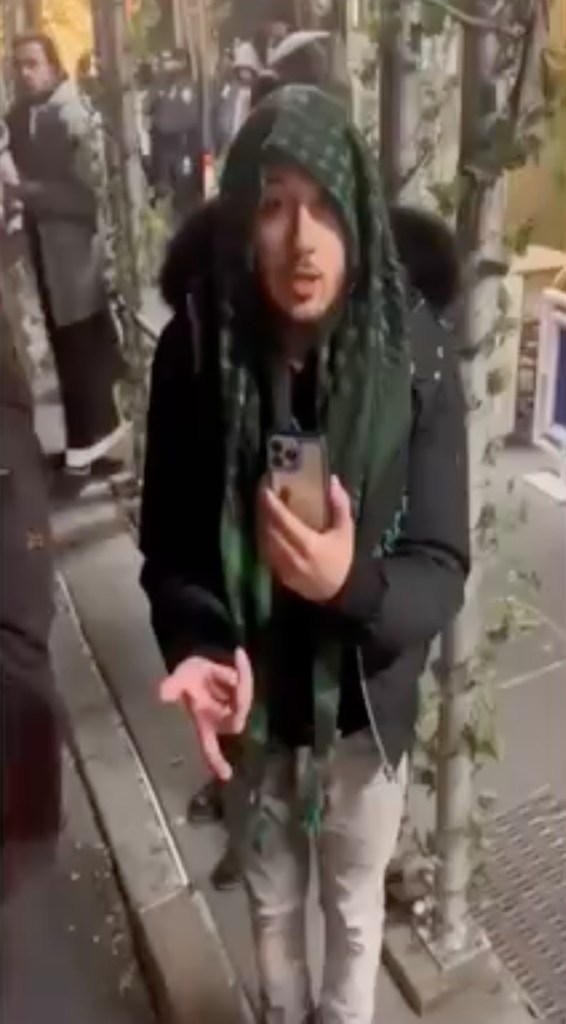 A man can be seen in CCTV footage wearing a green scarf and holding a phone