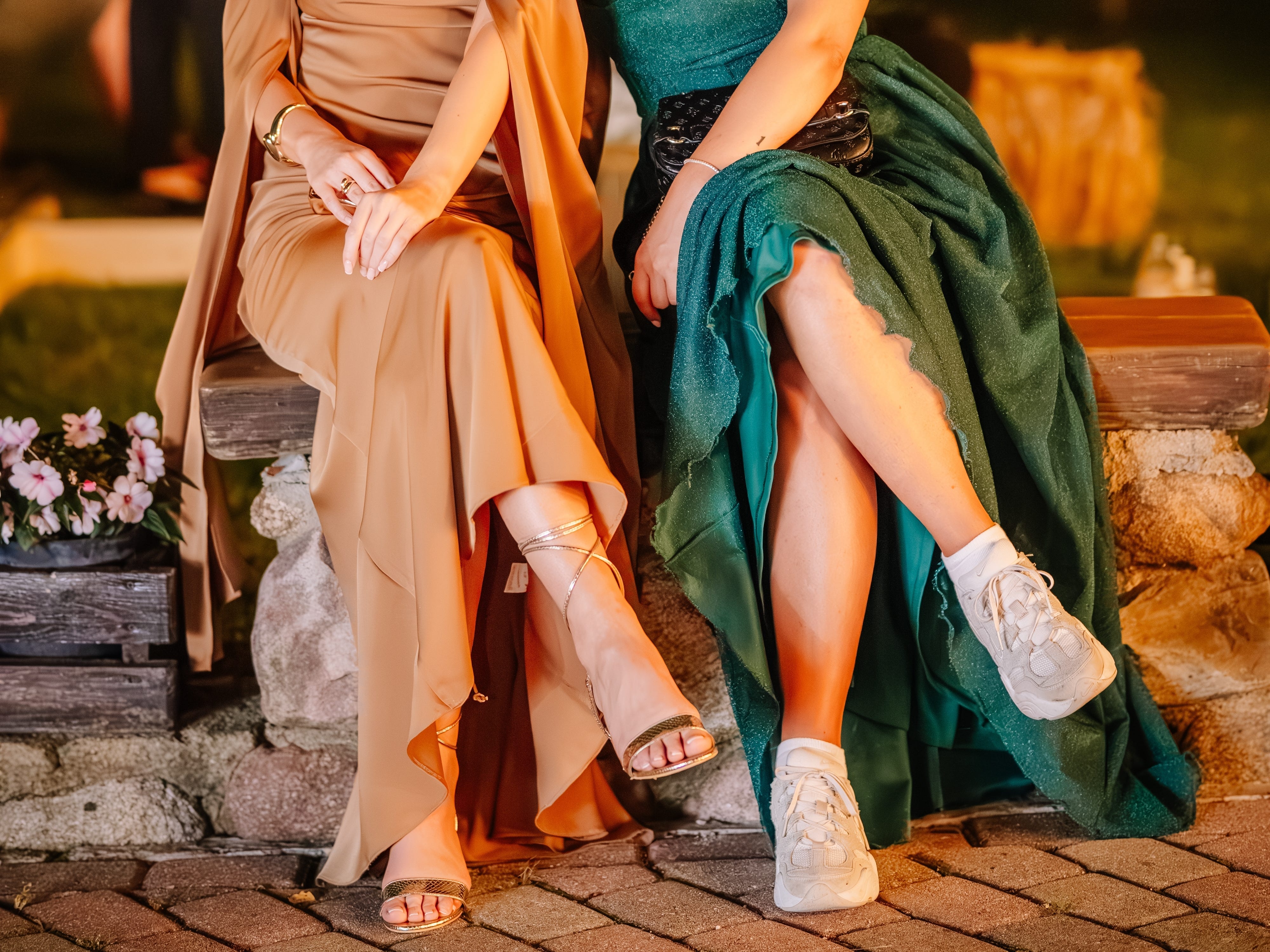 Two women in gowns, one of which is wearing dirty sneakers.