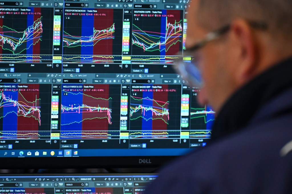 A trader looking at multiple stock market charts on a computer screen.