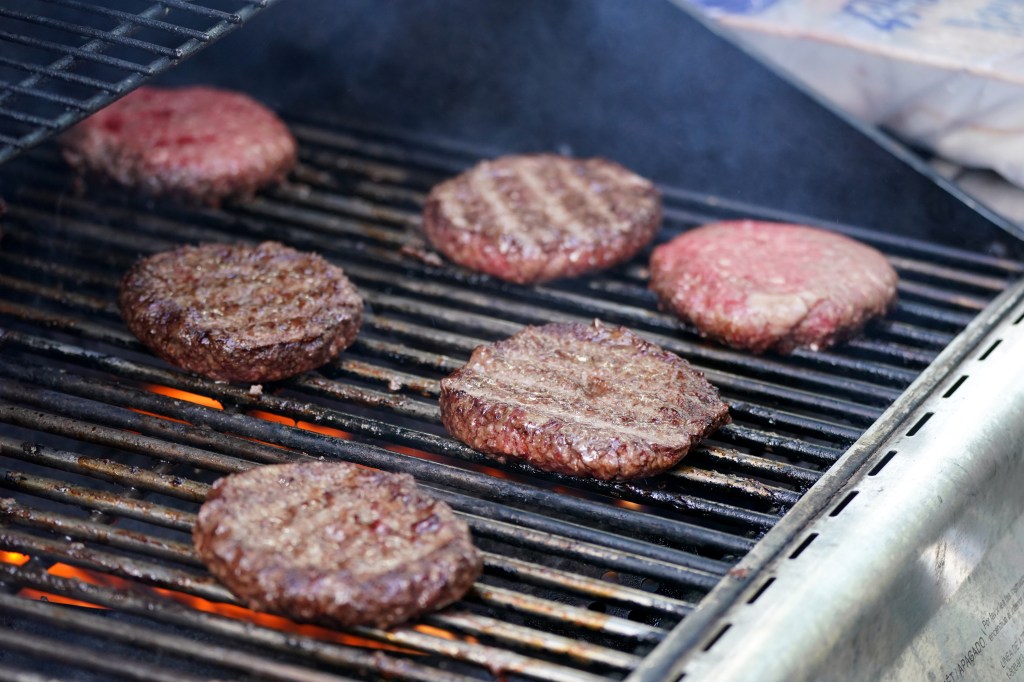 Hamburger patties grilling on a barbecue.