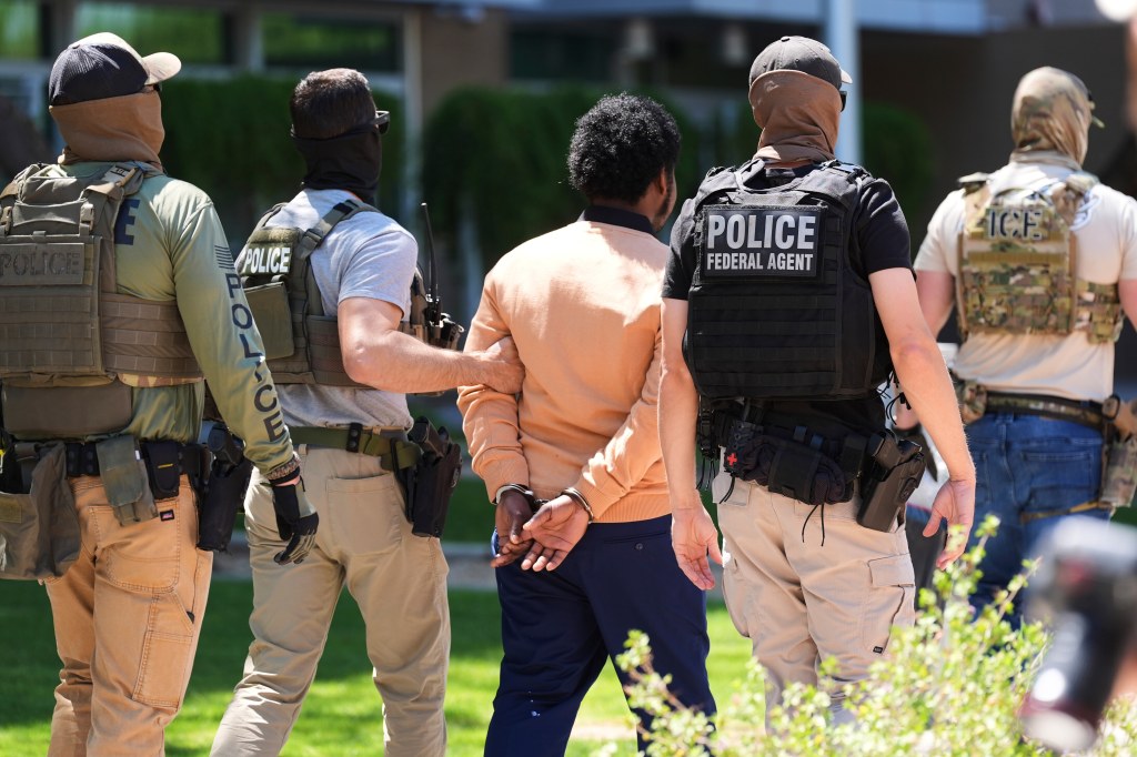 Person in handcuffs escorted by law enforcement officers.