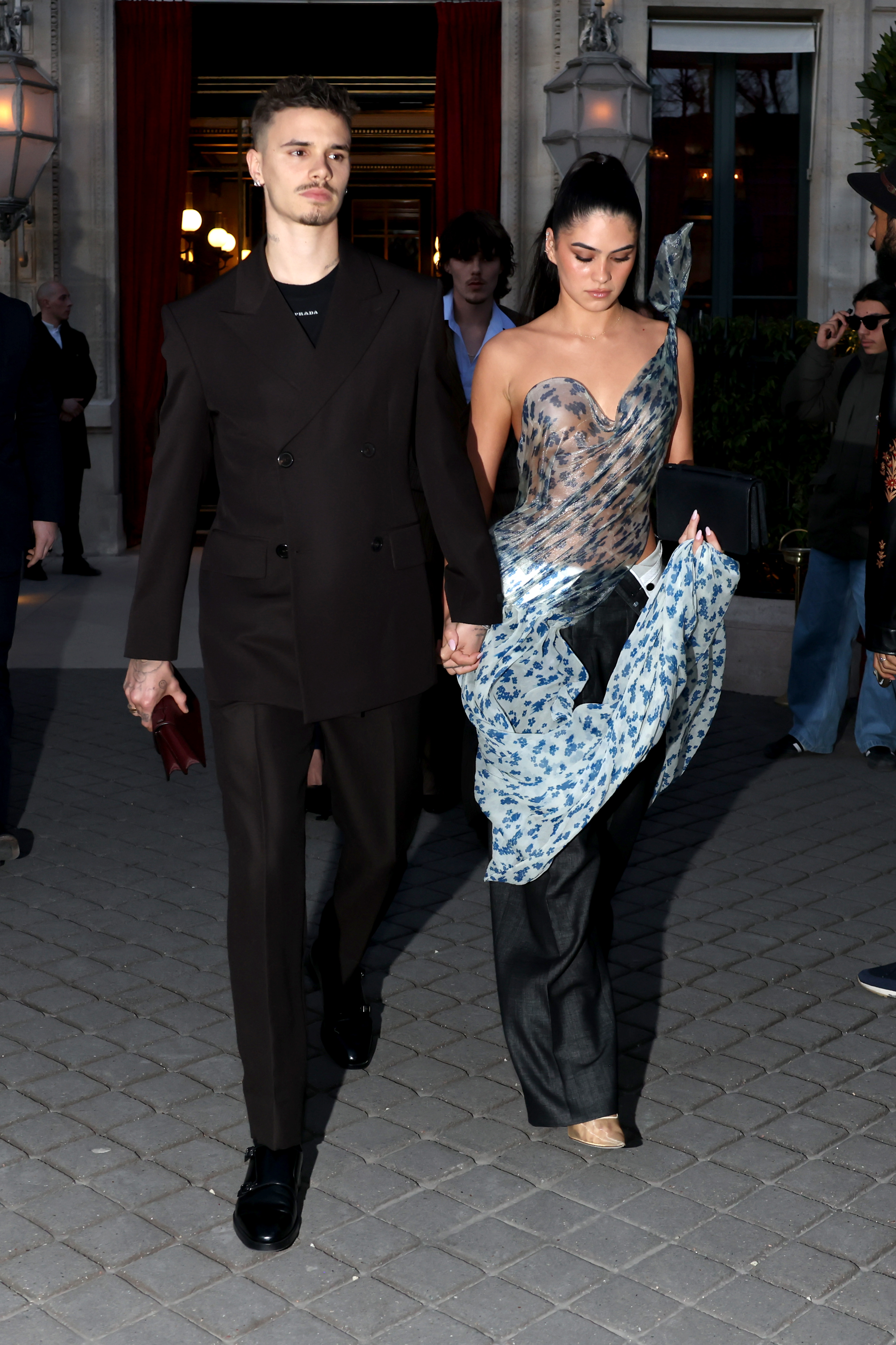 Romeo Beckham and Kim Turnball walk outdoors. 