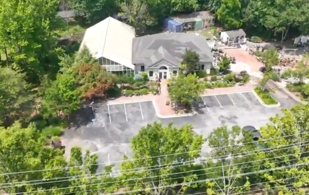 Aerial view of a commercial building with parking lot and surrounding greenery.