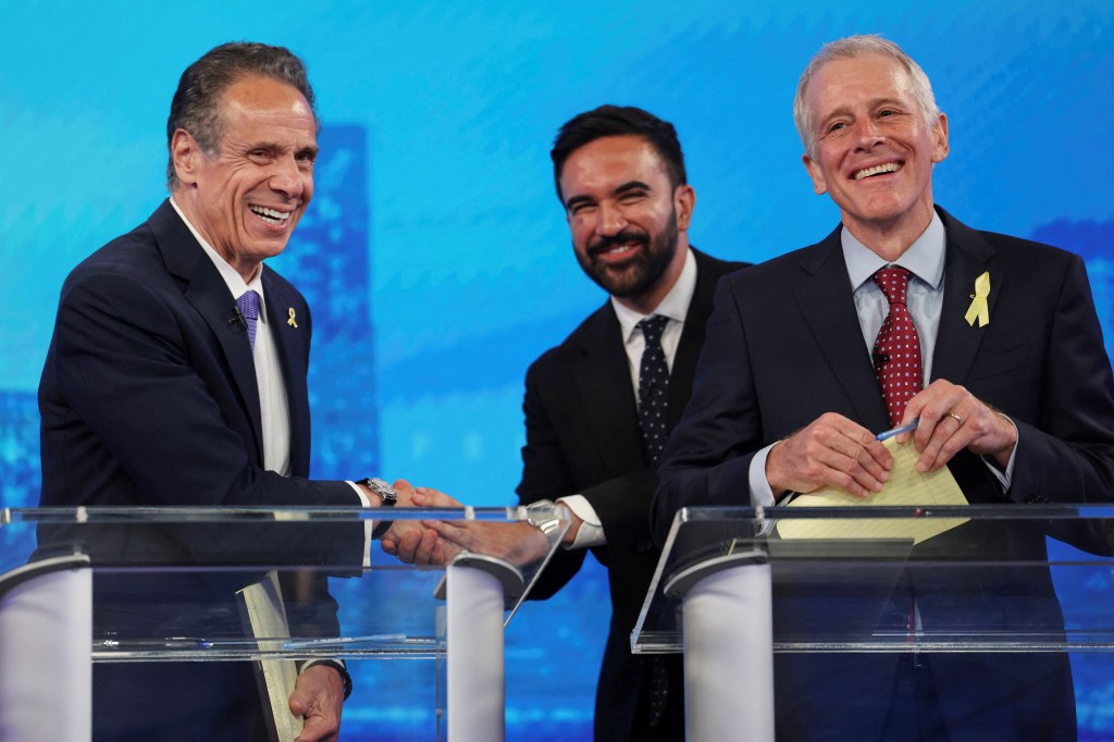Democratic mayoral candidate Andrew Cuomo shakes hands with fellow candidate Zohran Mamdani behind Whitney Tilson at the beginning of the NYC Democratic mayoral primary debate on June 4, 2025.  