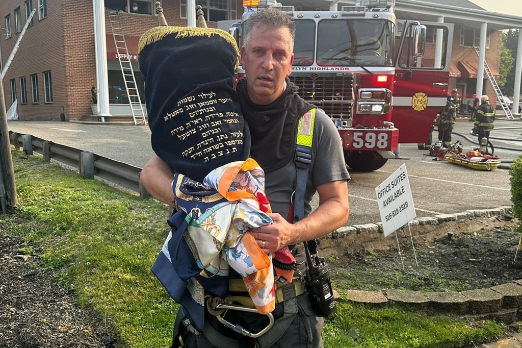 Firefighter carrying a Torah scroll rescued from a fire.