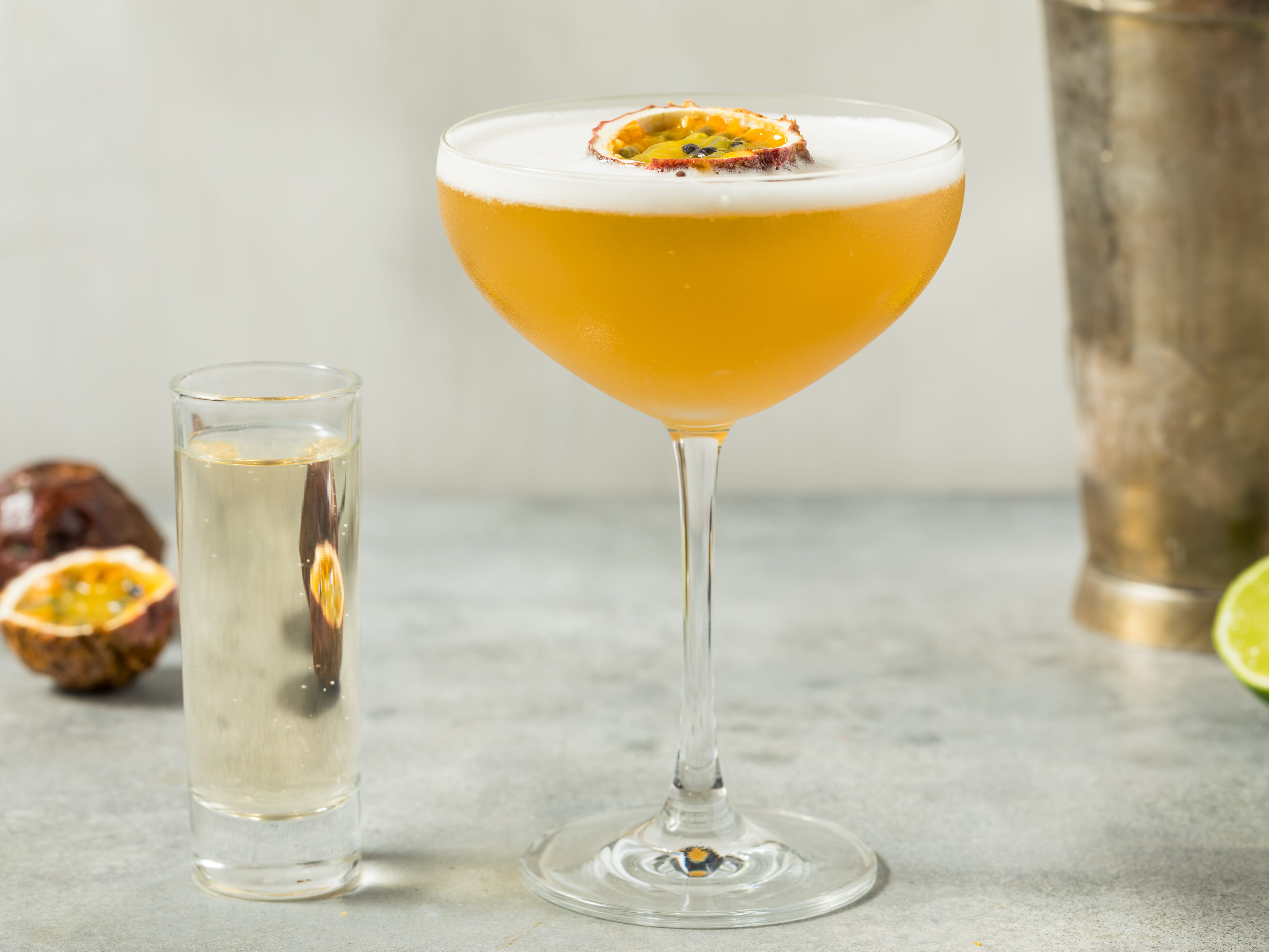 A passion-fruit cocktail in a martini glass and a full shot glass.