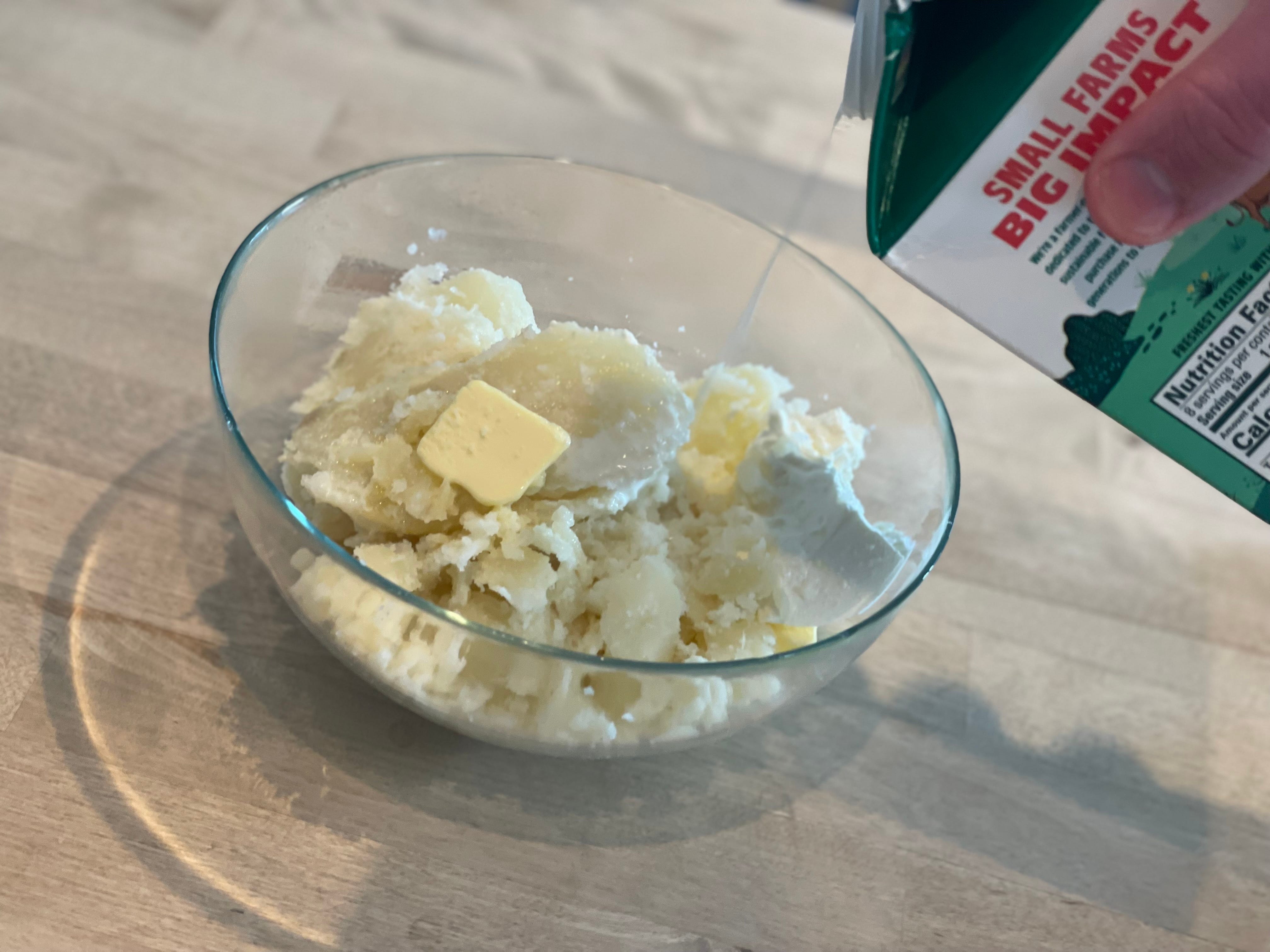 Steven pours milk into a bowl with potatoes and butter.