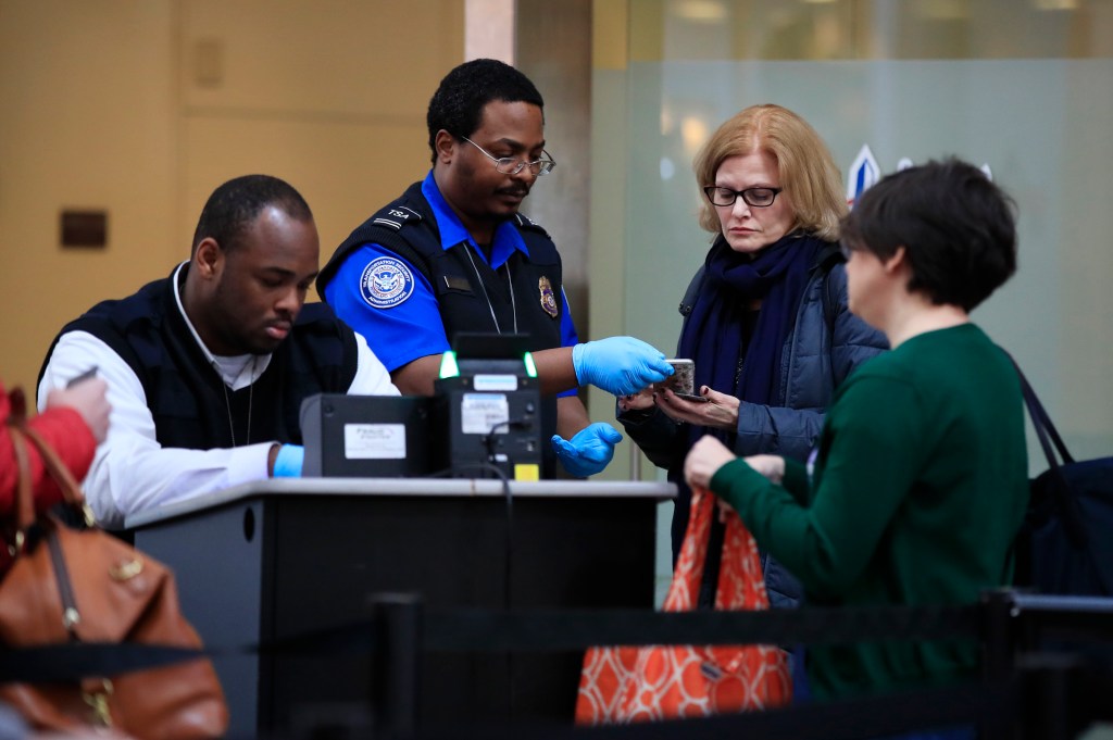TSA agents screening passengers at an airport security checkpoint.